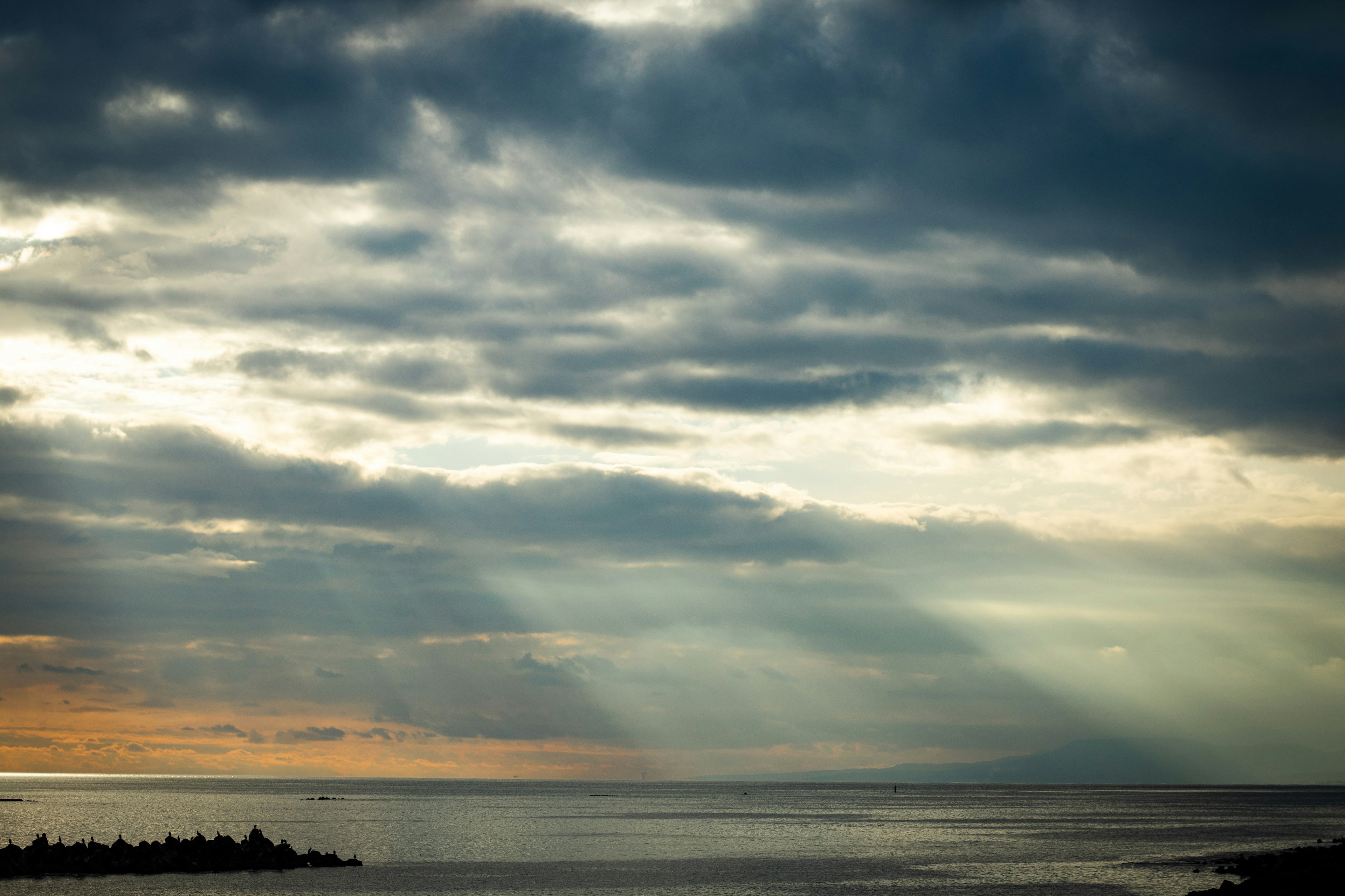 穏やかな海と雲が広がる風景、夕暮れの光が差し込む