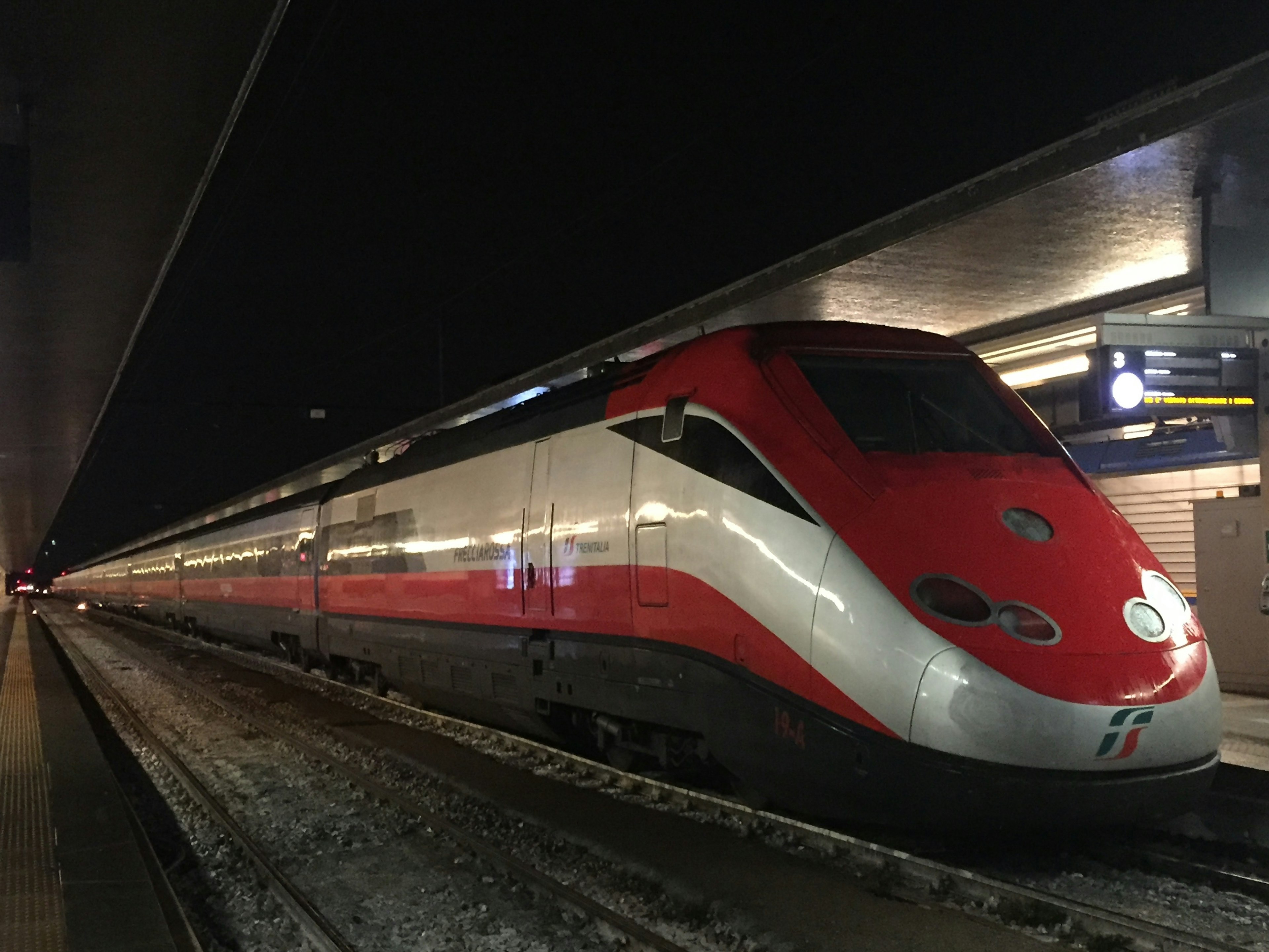 赤と白の高速列車が夜の駅で停車中