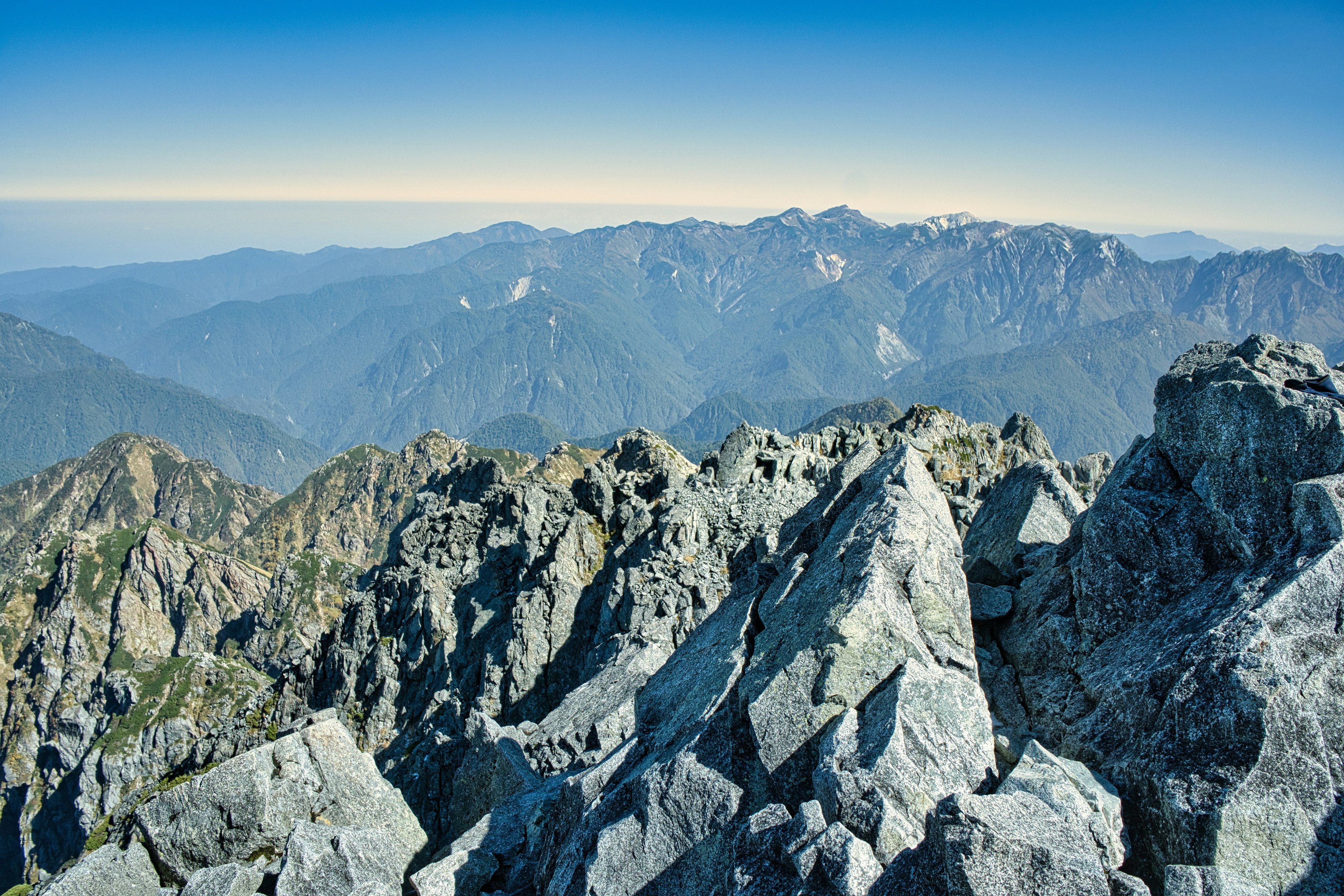 Aussicht vom Berggipfel mit scharfen Felsen und entfernten Bergen