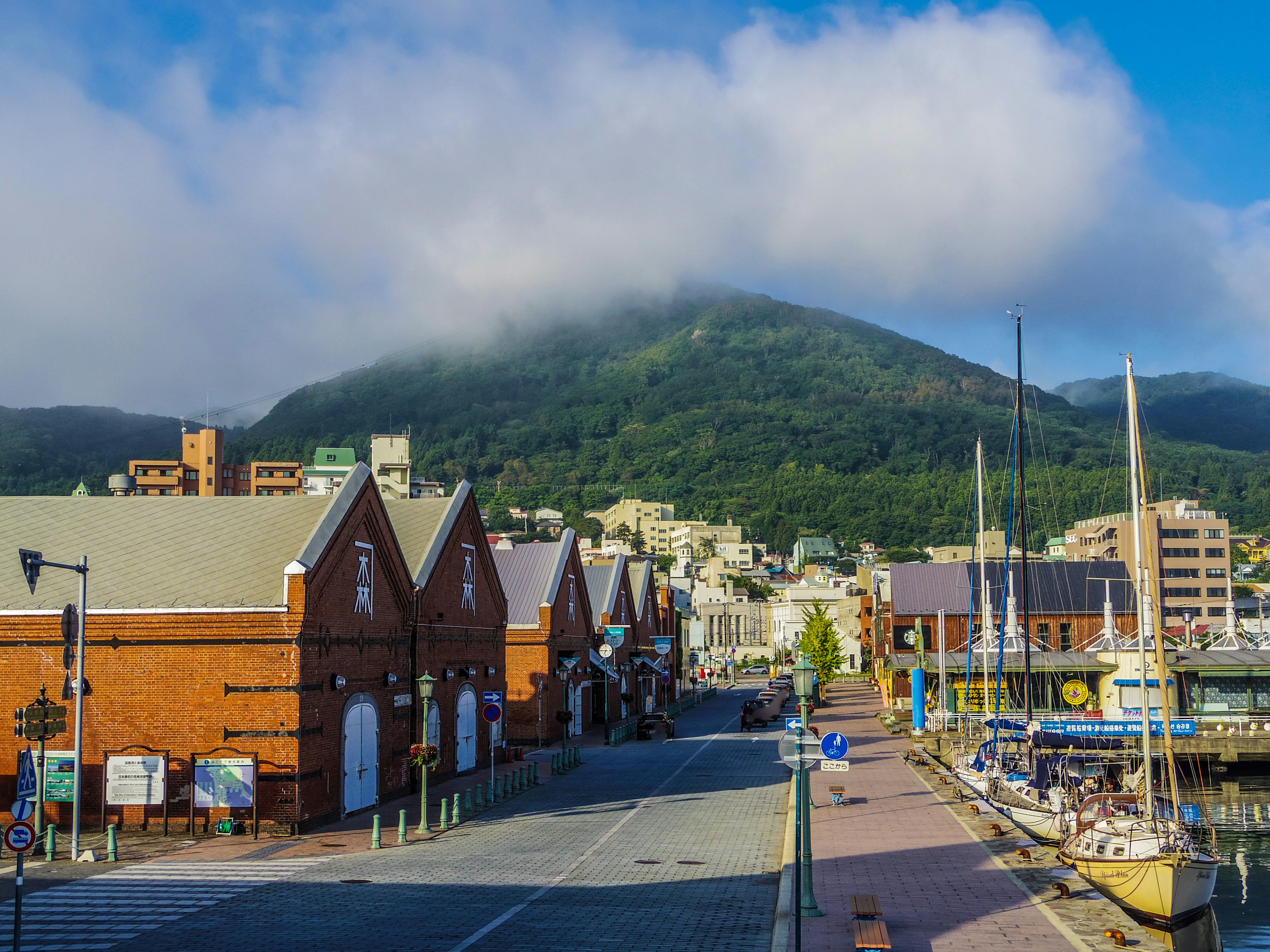 赤レンガの建物と山の風景が広がる港町の風景