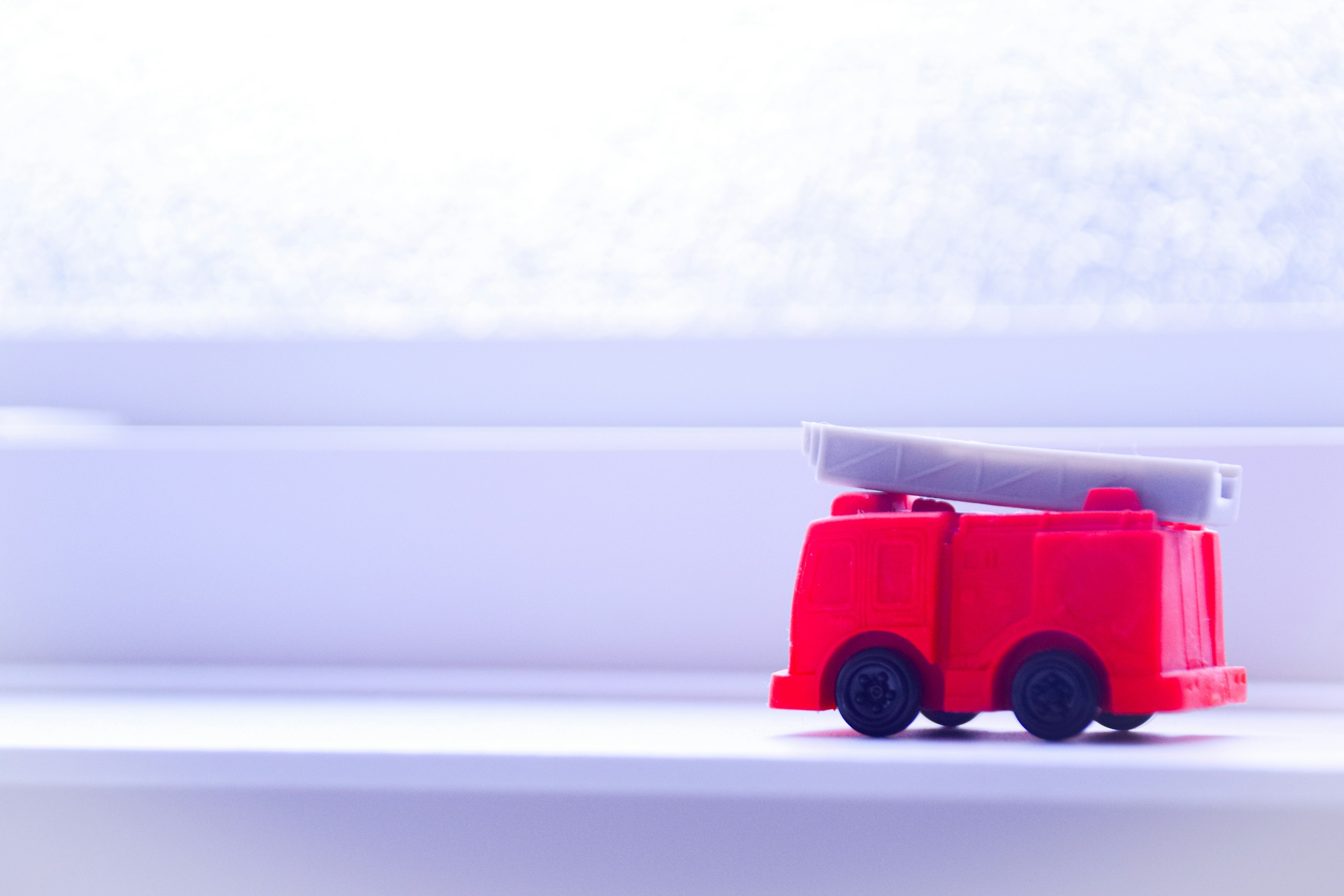 A red toy fire truck placed on a windowsill