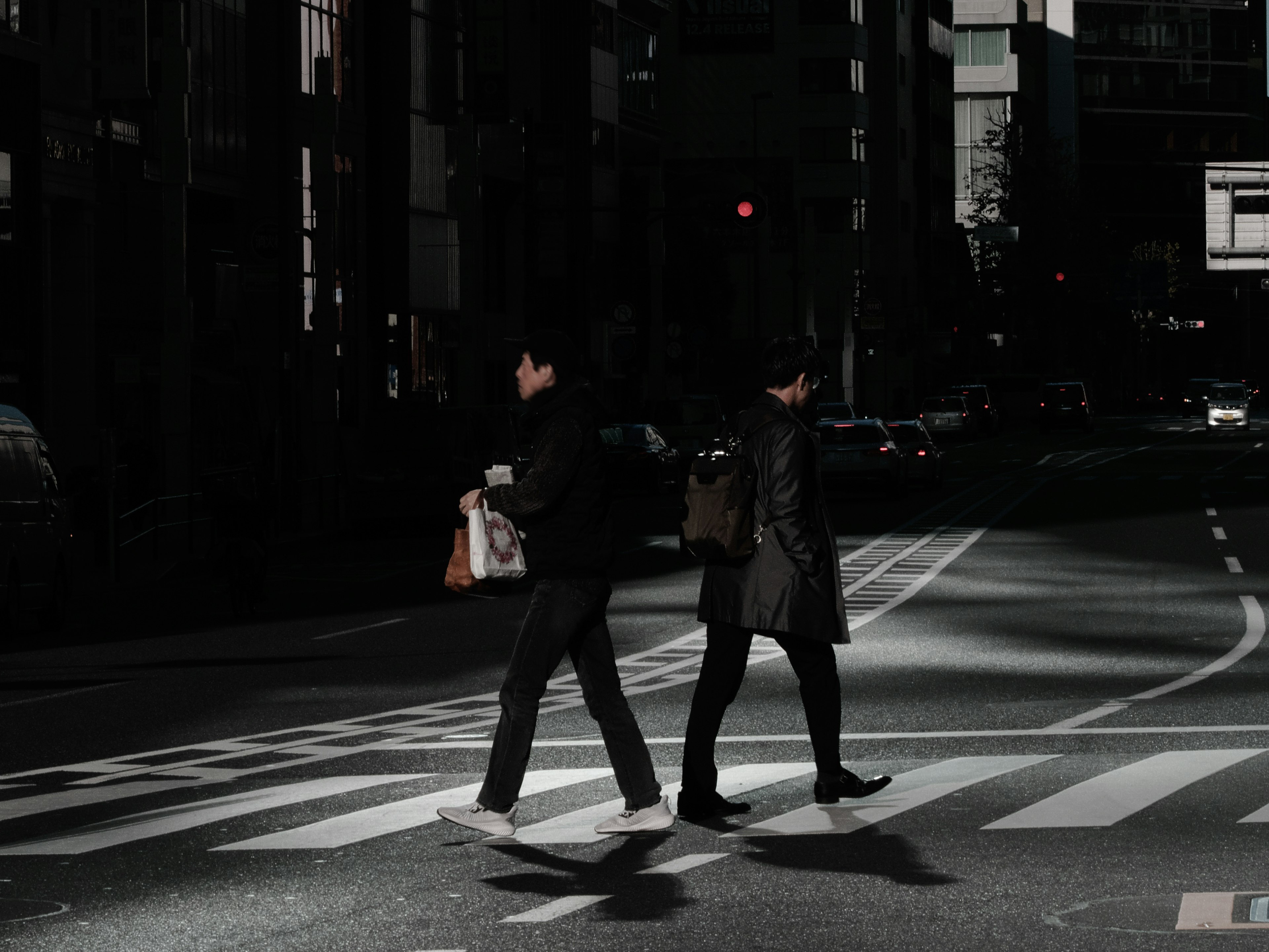 夜の都市で横断歩道を渡る二人の人物と街の灯り