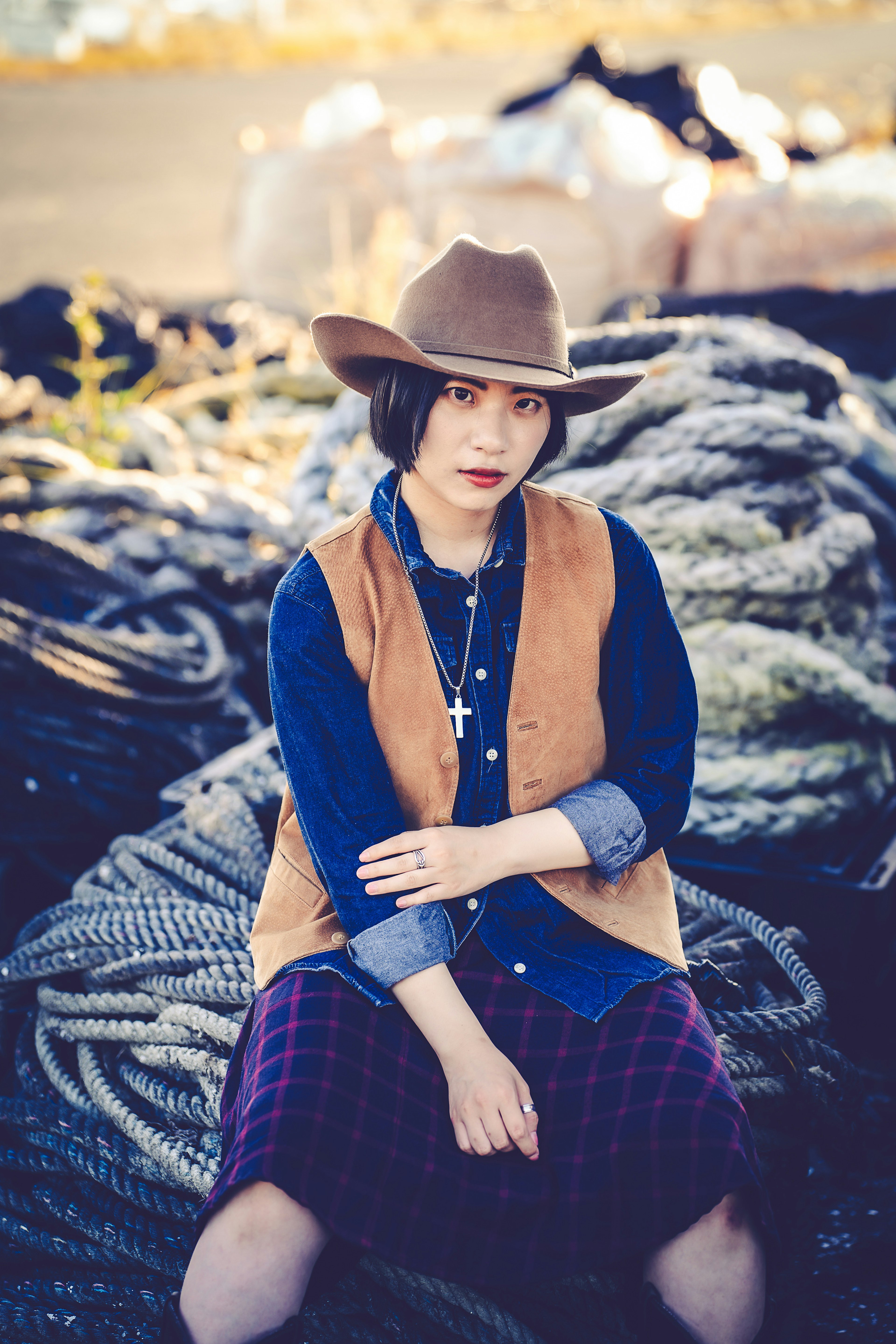 Une femme portant un chapeau de cowboy et une chemise en denim est assise sur un tas de cordes