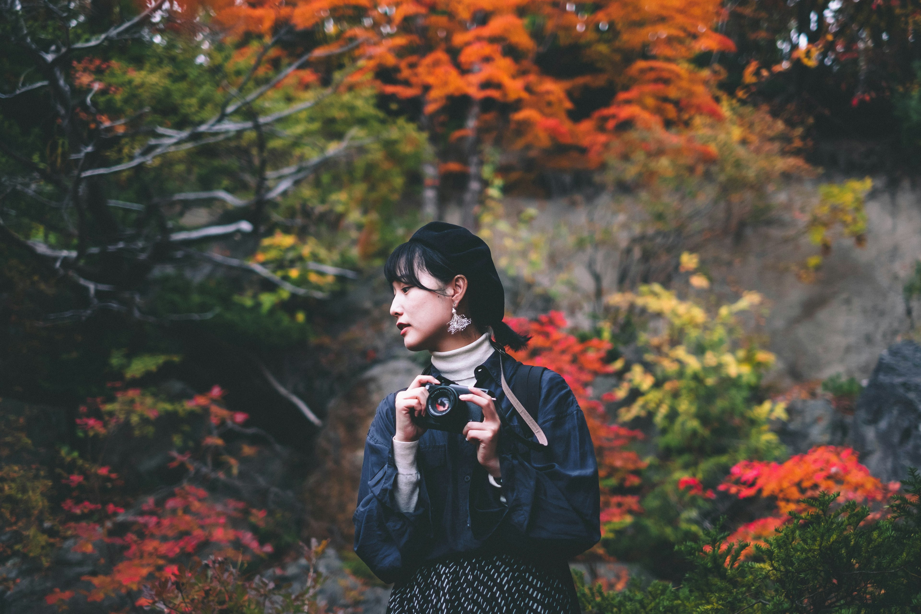 Portrait d'une femme tenant un appareil photo dans un feuillage d'automne