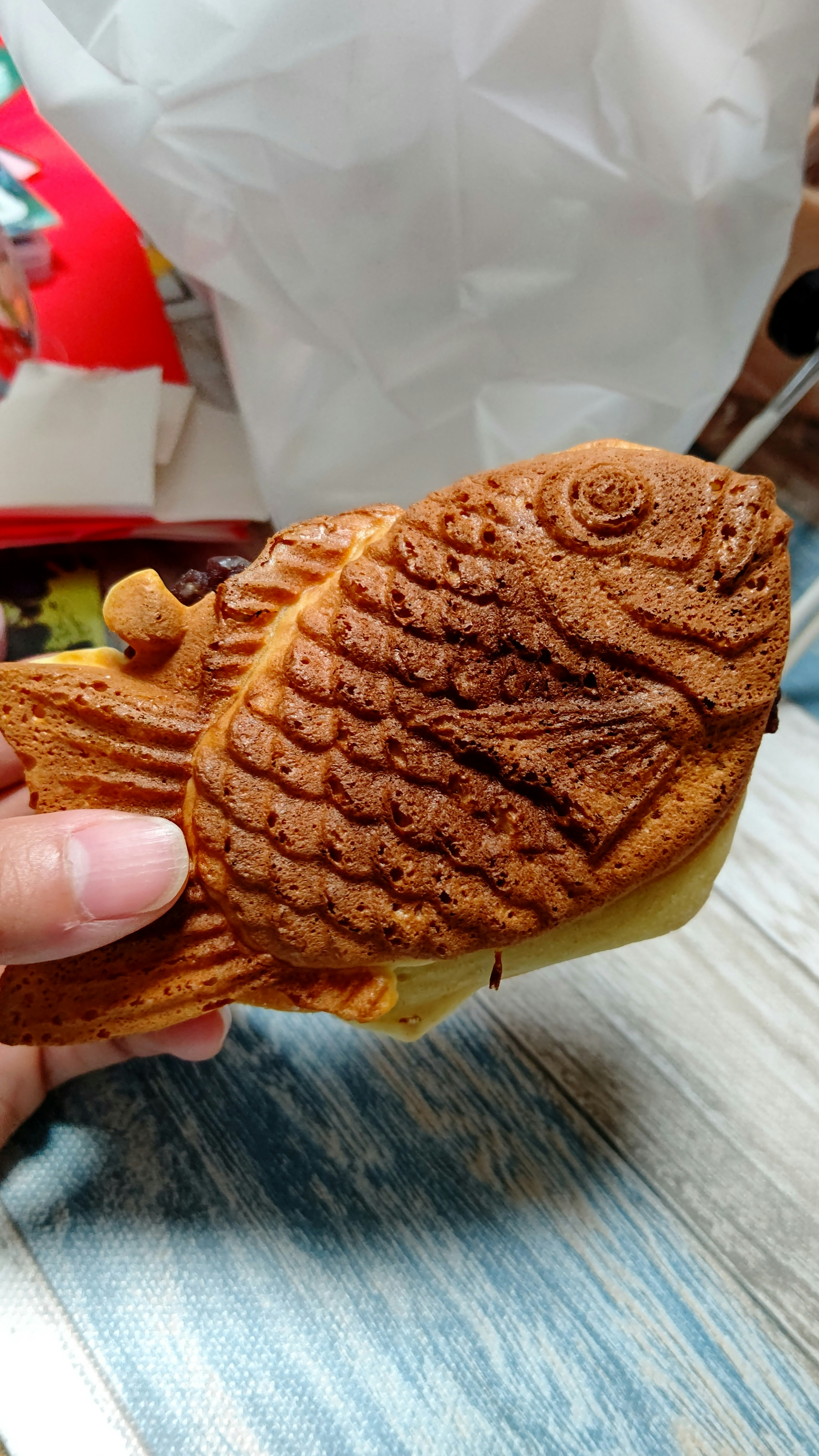 Image of taiyaki held in hand with a golden-brown exterior shaped like a fish