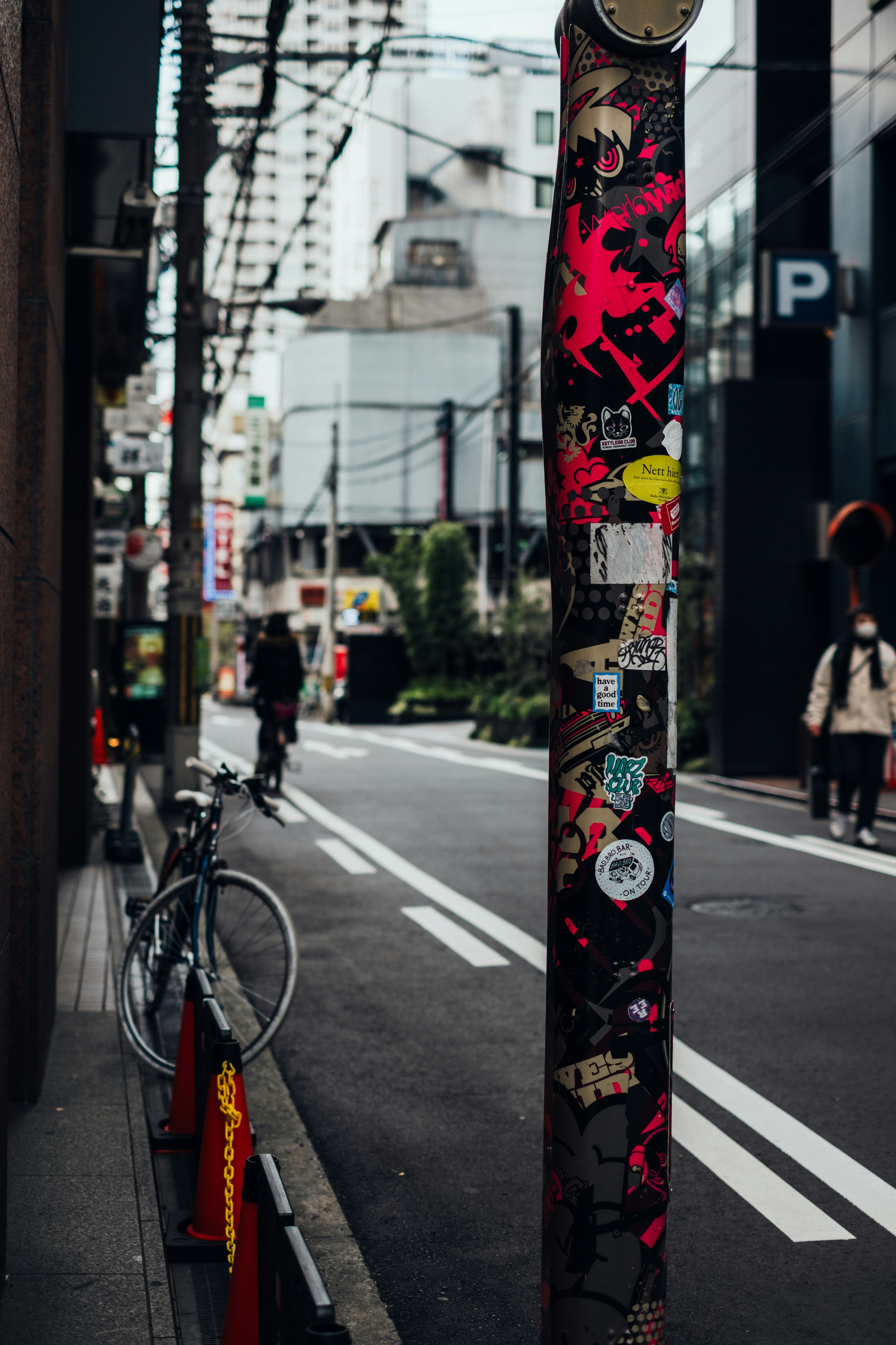 Urban scene featuring a pole covered in street art stickers and a bicycle