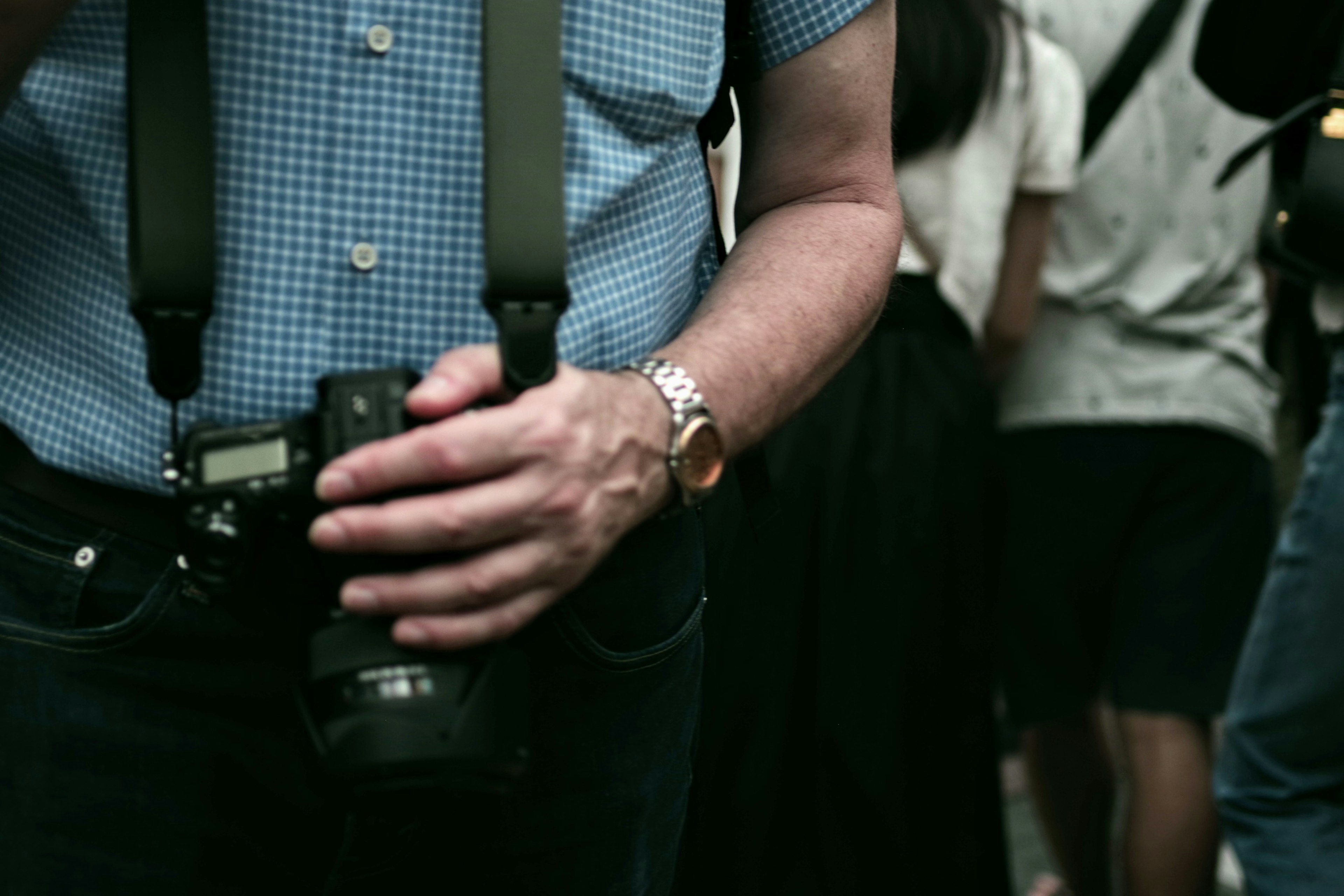 Man holding a camera wearing a checkered shirt