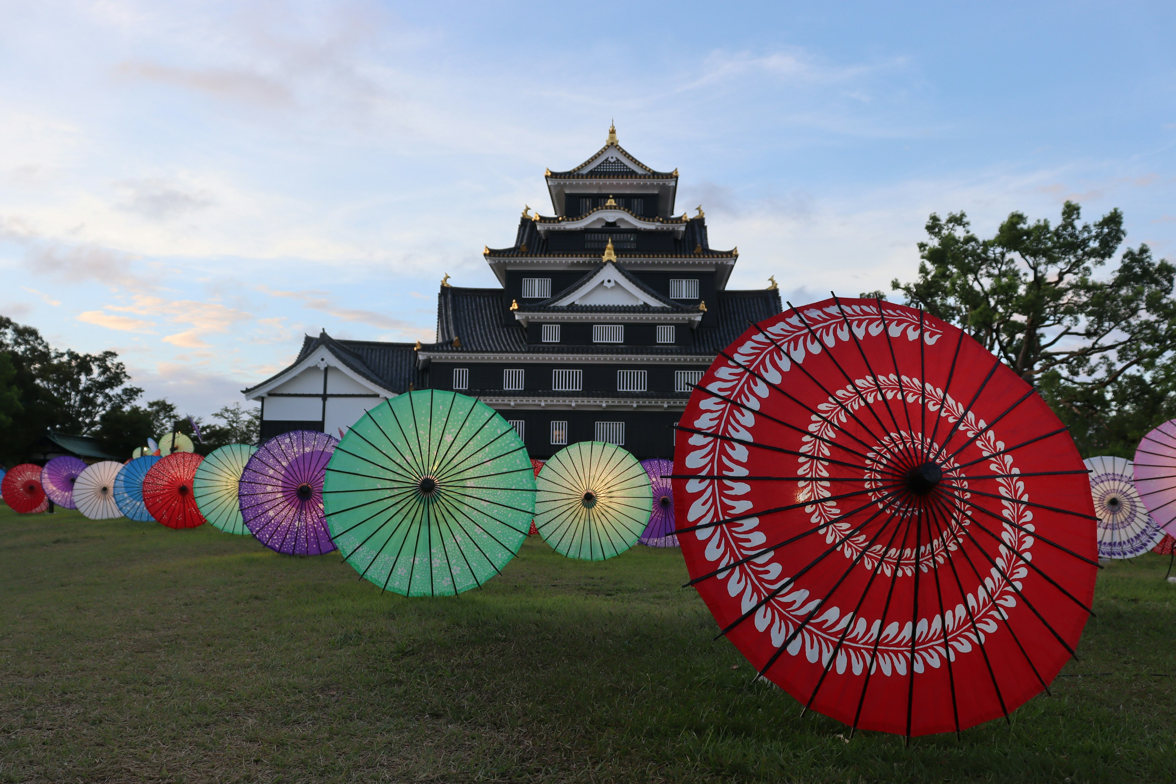 美しい和傘が並ぶ背景に黒い城がそびえる風景