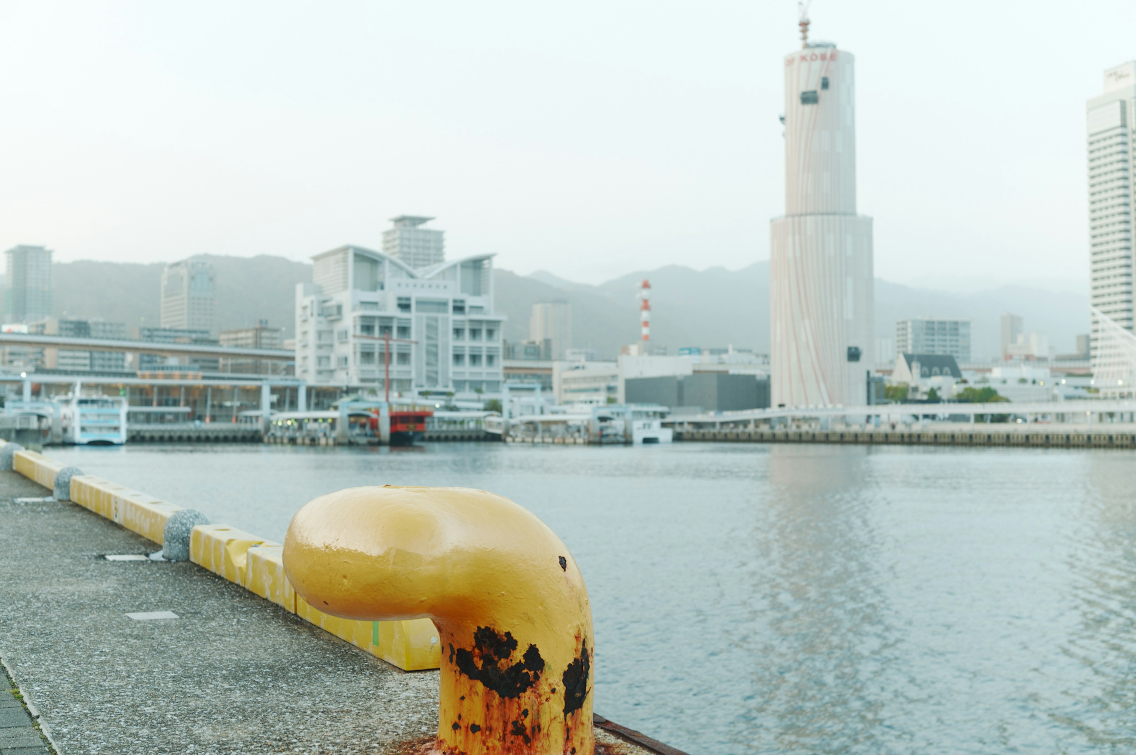 Yellow mooring bollard at the harbor with distant buildings