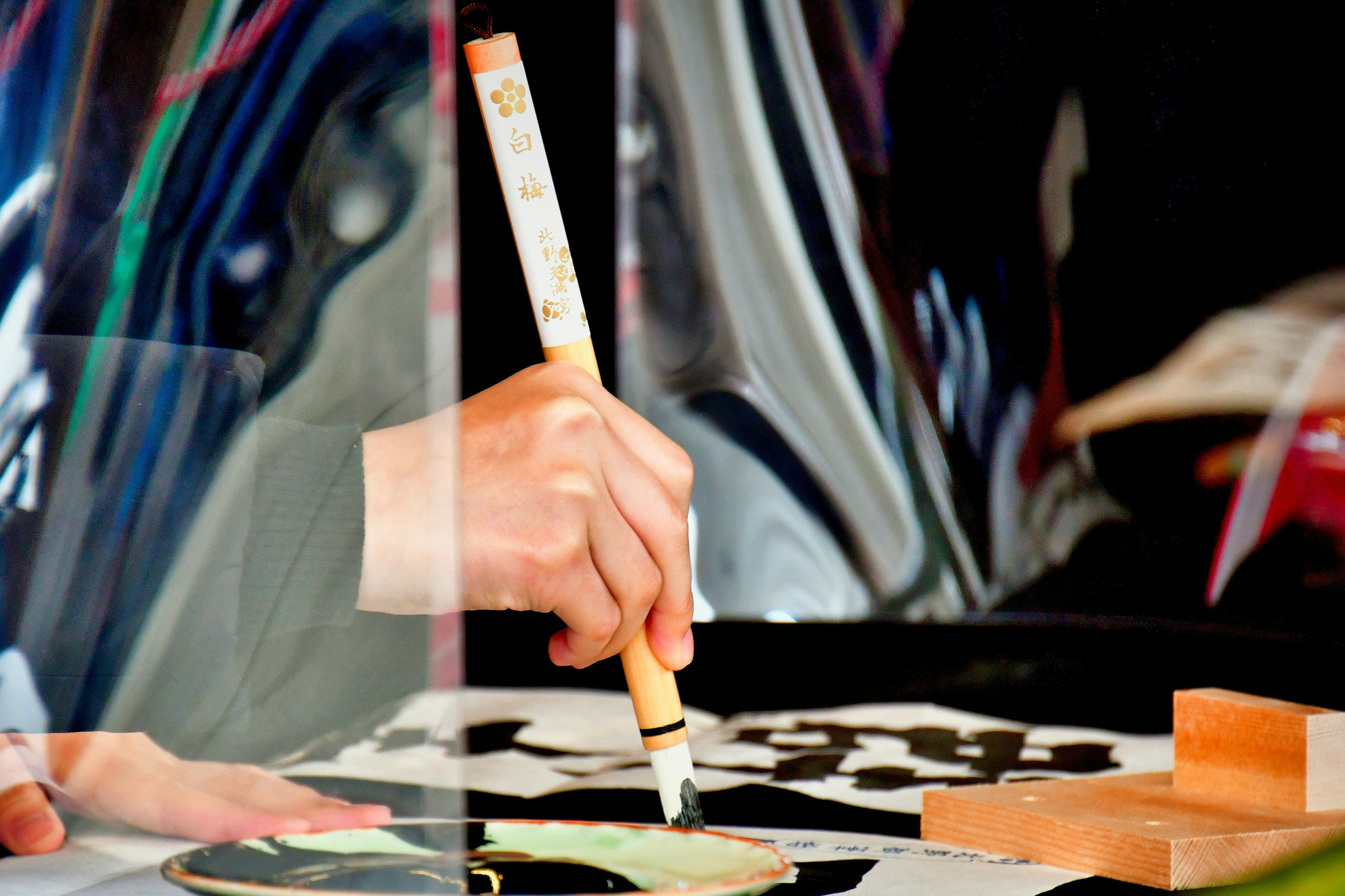 A person holding a brush painting on colorful tiles