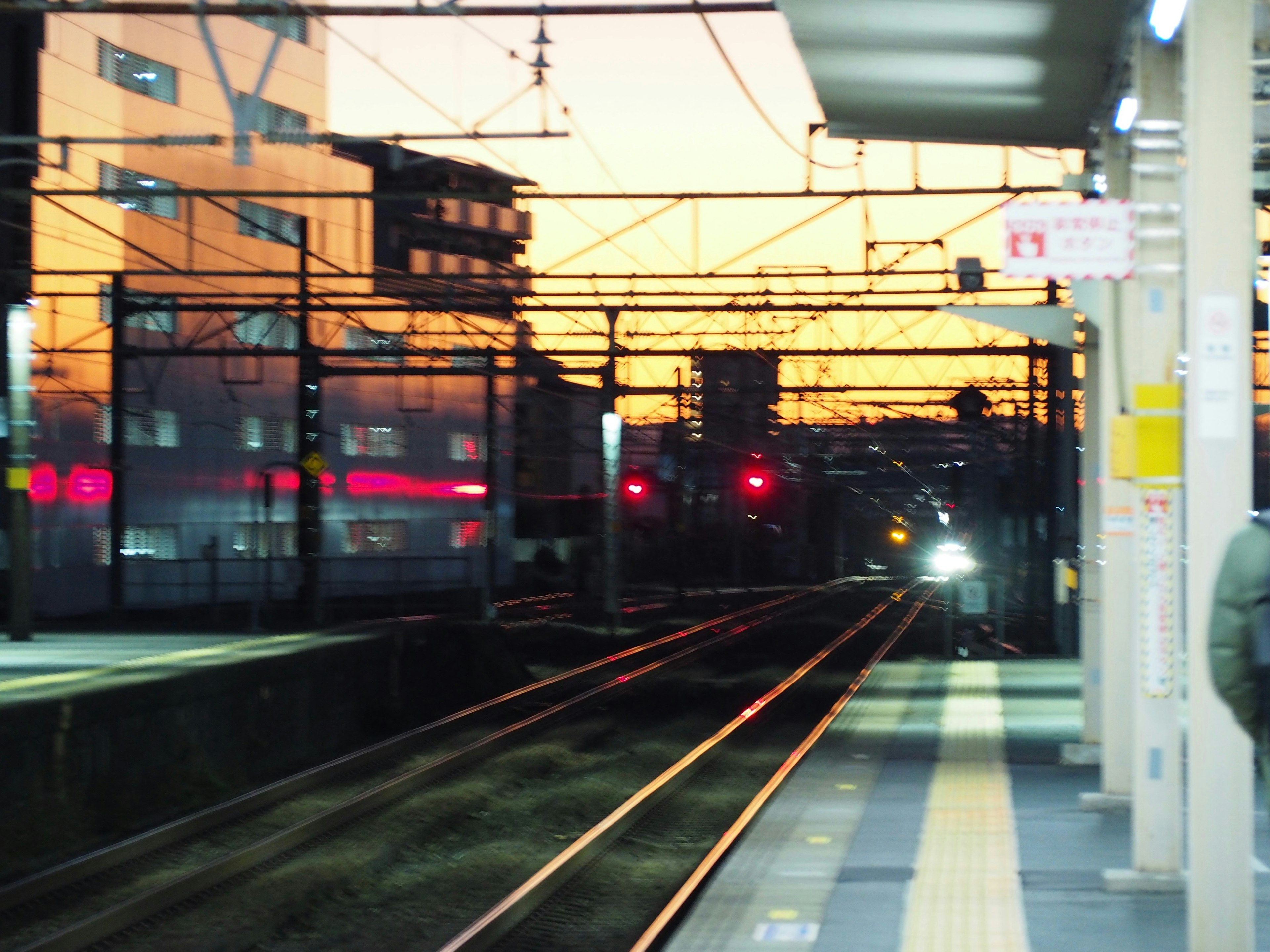 Train station at sunset with visible tracks and signals