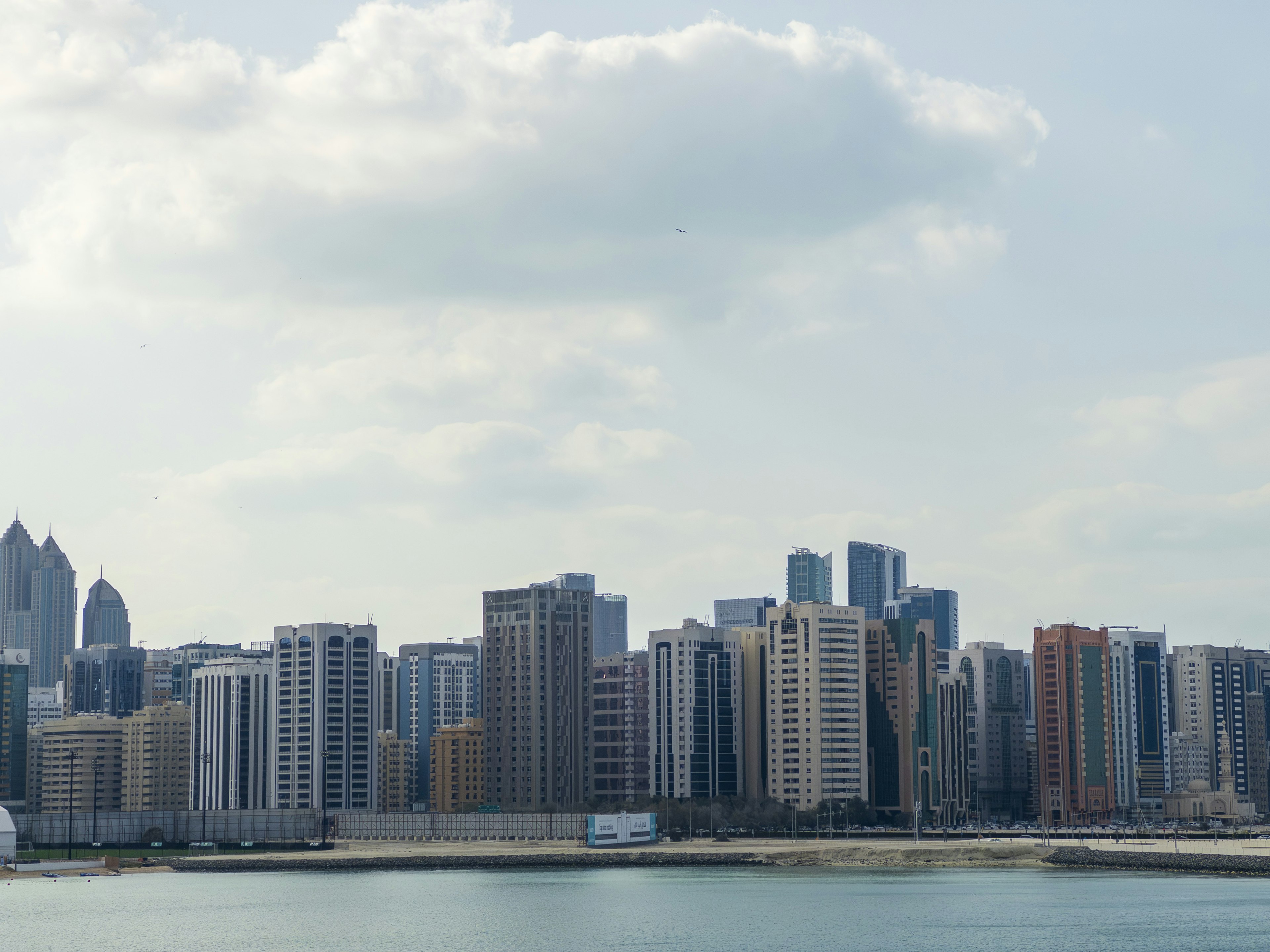 Garis langit modern dengan gedung tinggi di sepanjang garis pantai di bawah langit biru