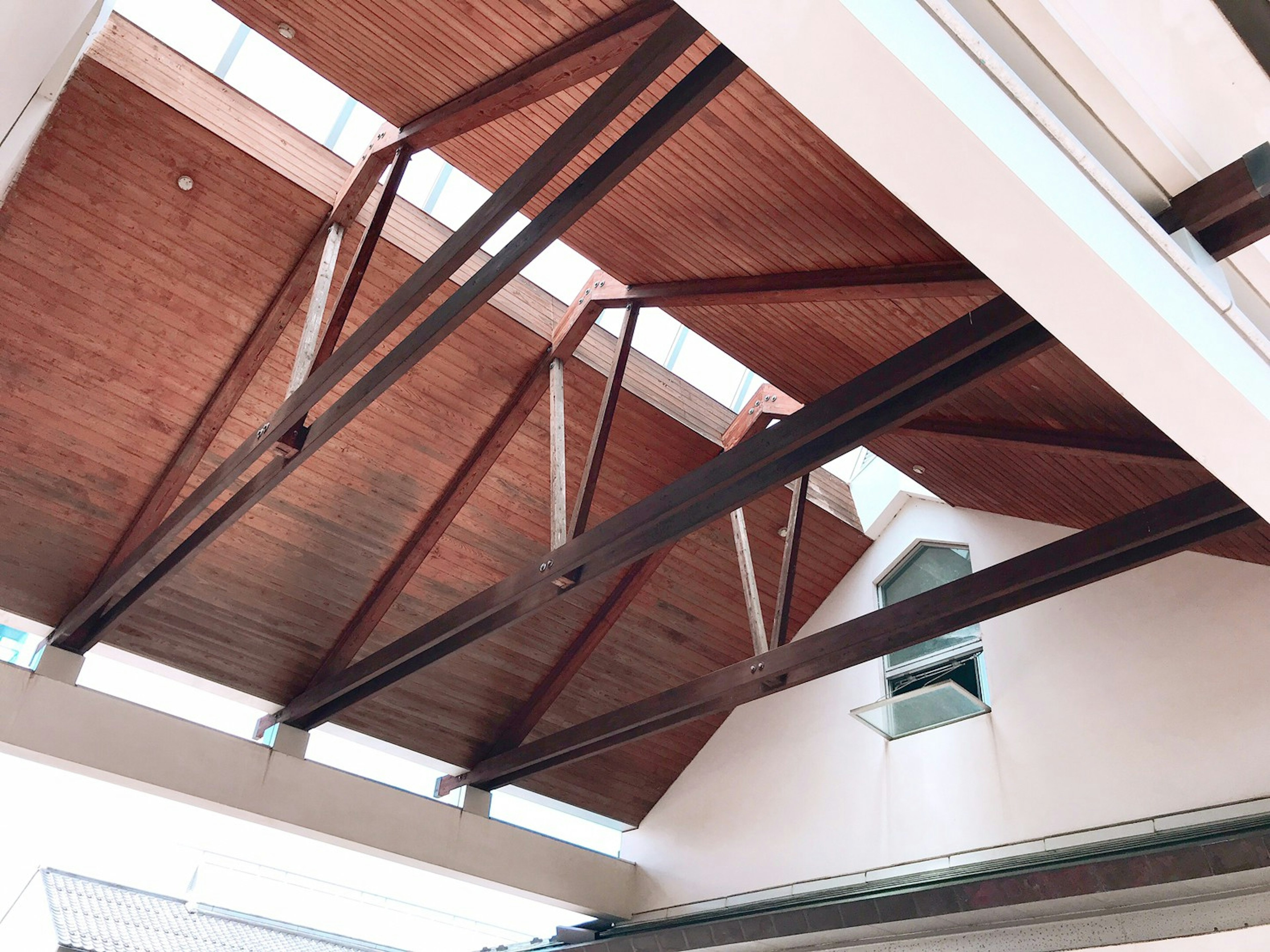 Modern indoor ceiling featuring wooden roof and metal beams