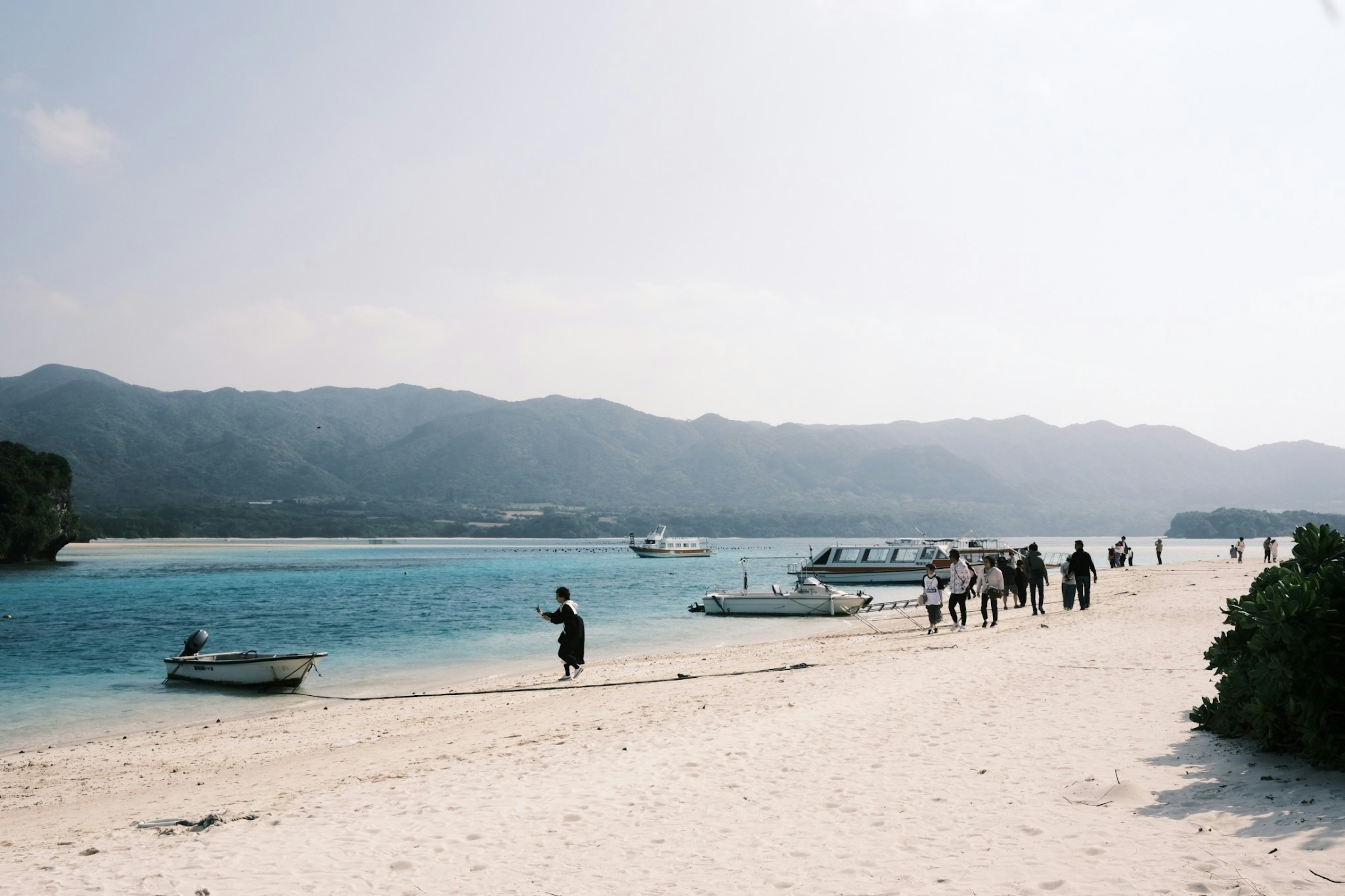 People walking on a beach with white sand and blue water