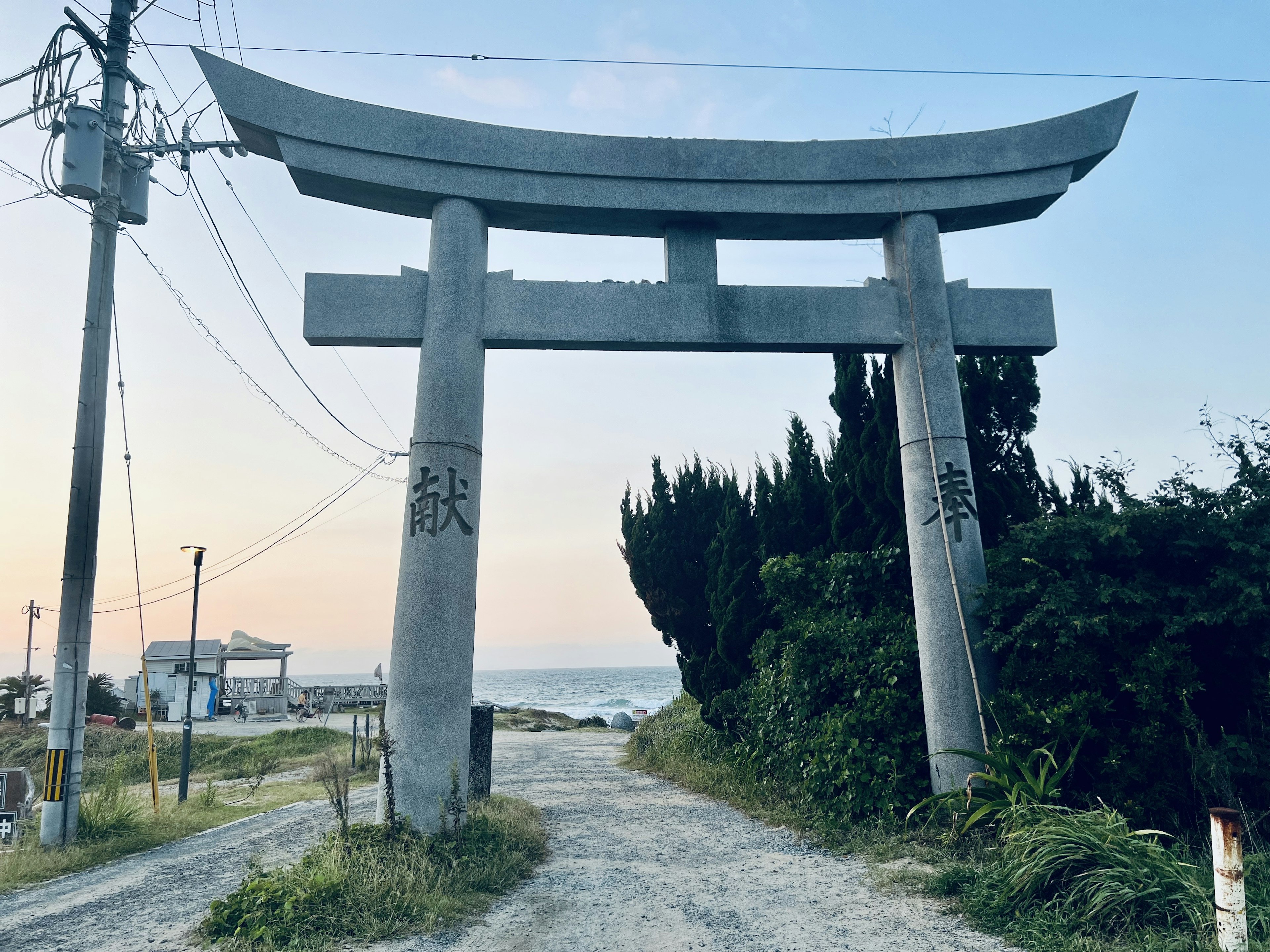 Puerta torii de piedra que conduce al mar a lo largo de un camino tranquilo