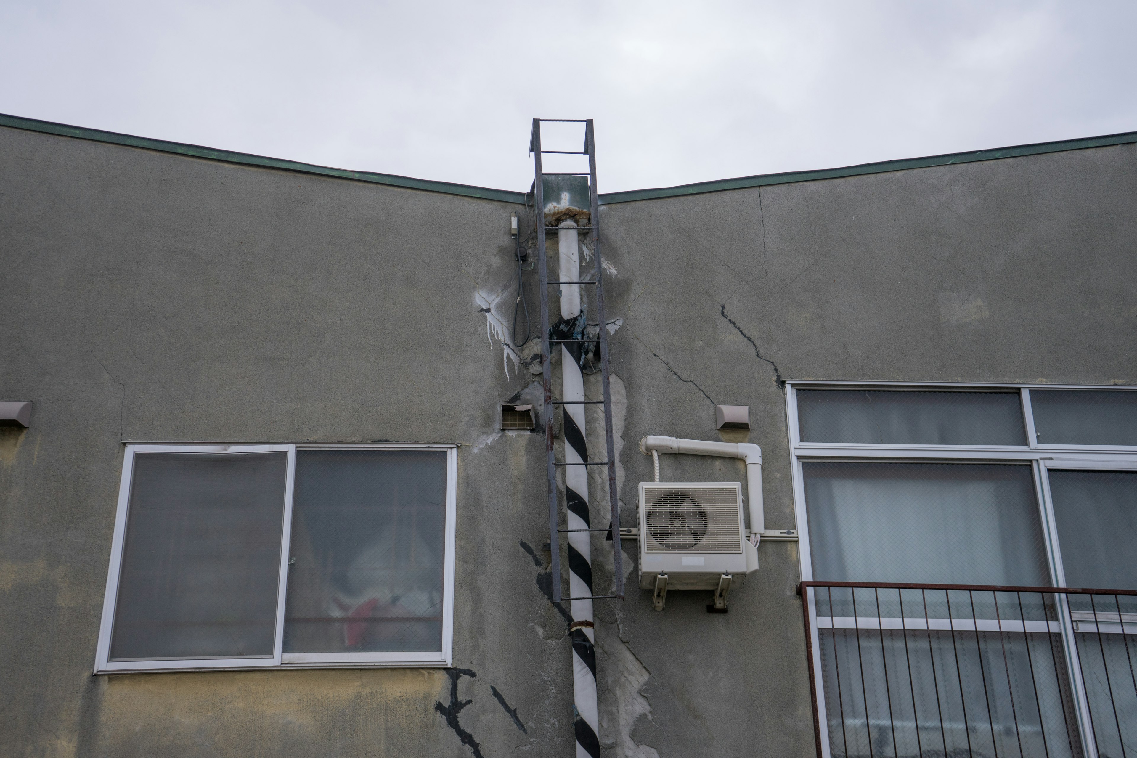 Graue Wand mit einer Klimaanlage und einer vertikalen Treppenstruktur