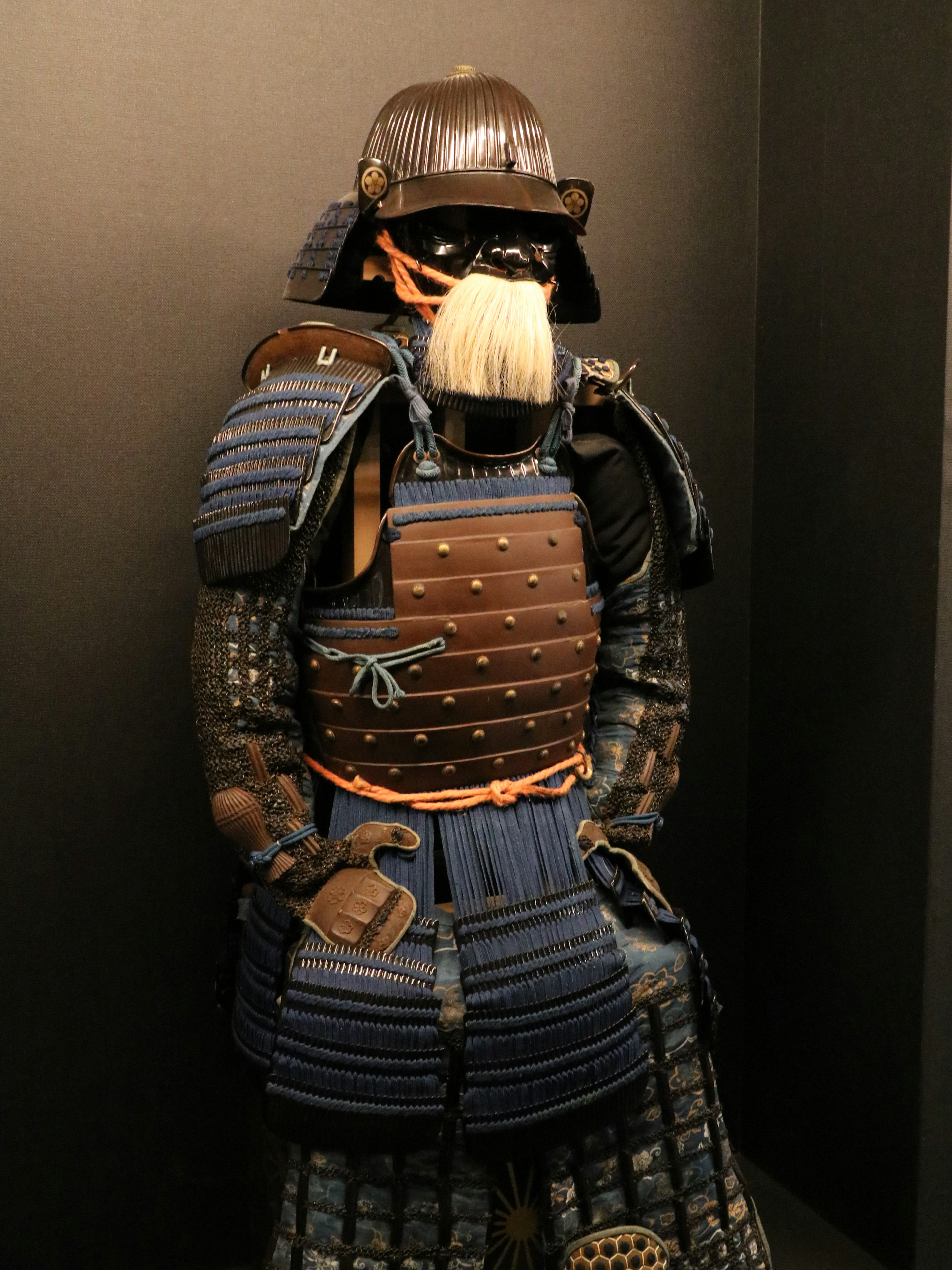 A mannequin dressed in samurai armor standing against a black background