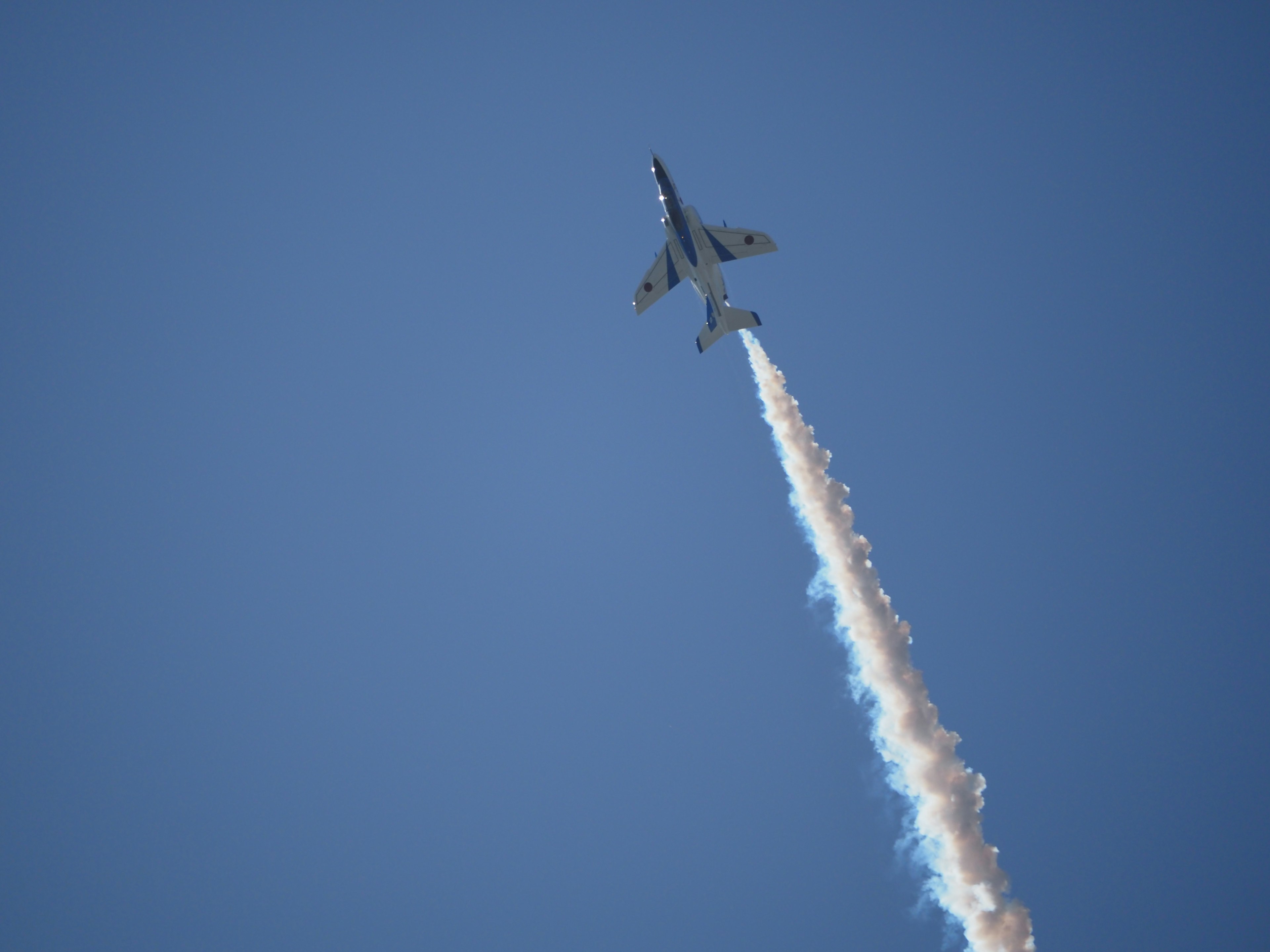 Pesawat jet yang naik melawan langit biru cerah dengan jejak putih