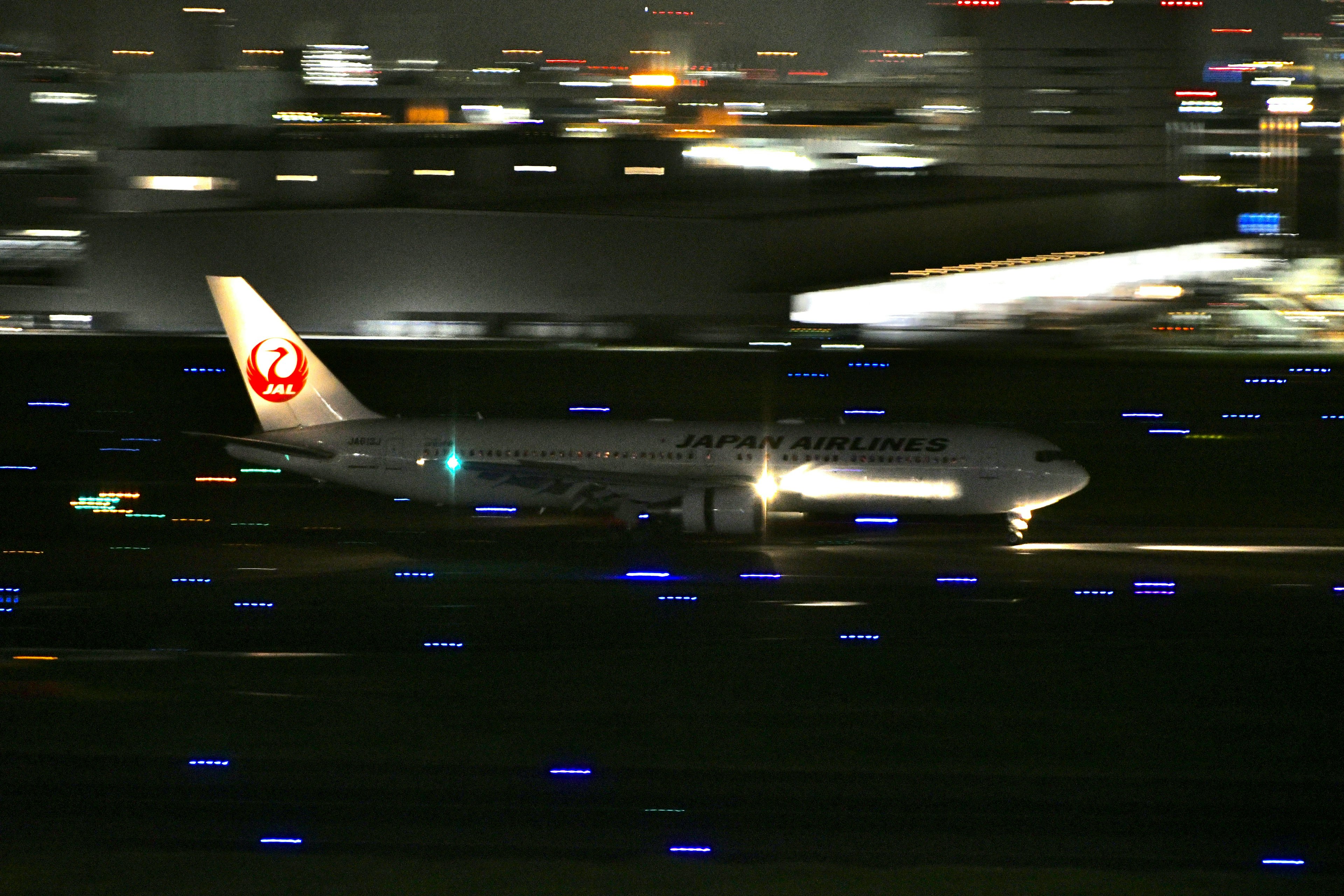 夜の空港で滑走路に着陸する日本航空の旅客機