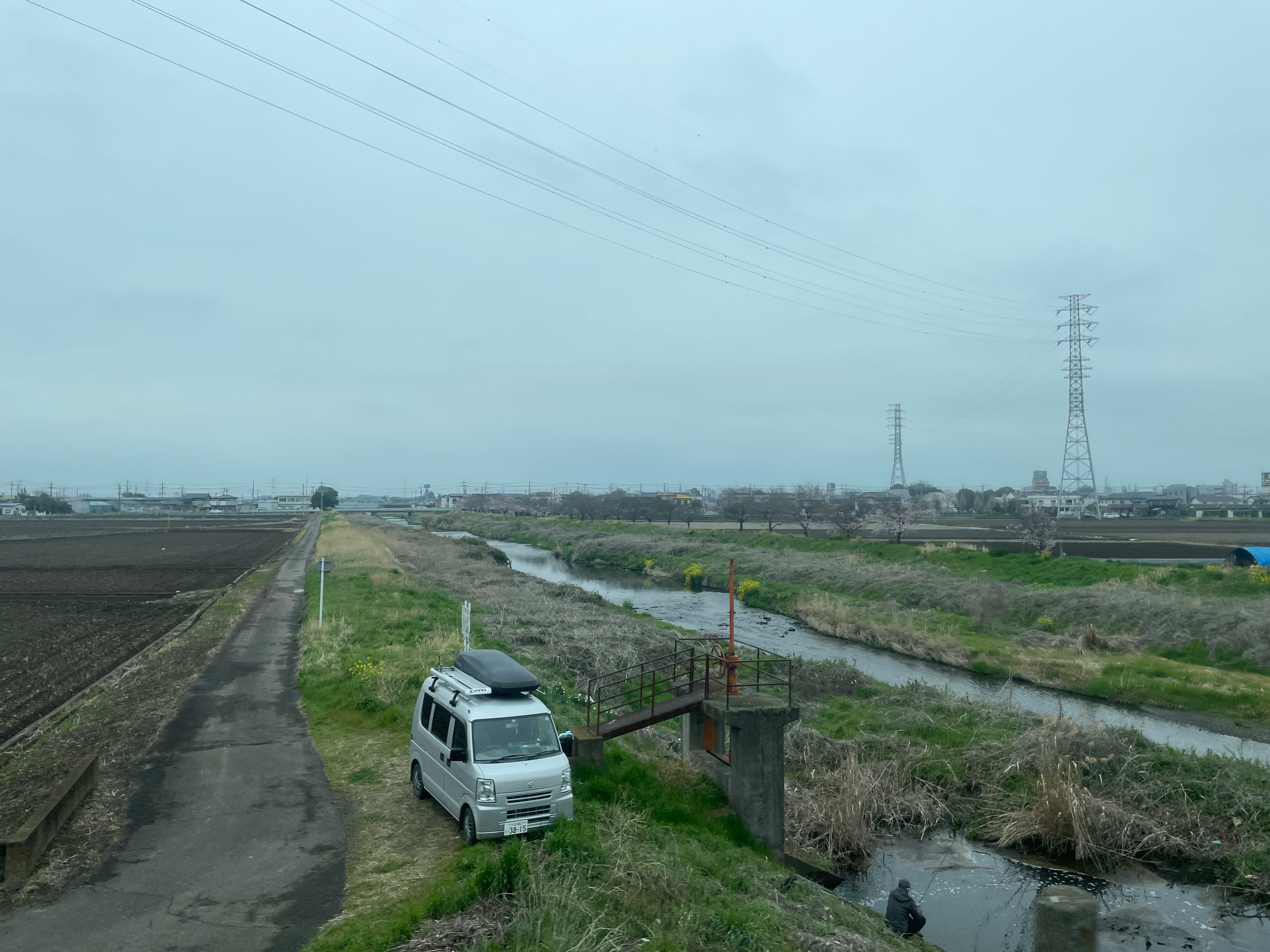 農地と小川が広がる風景に停まっている白い車