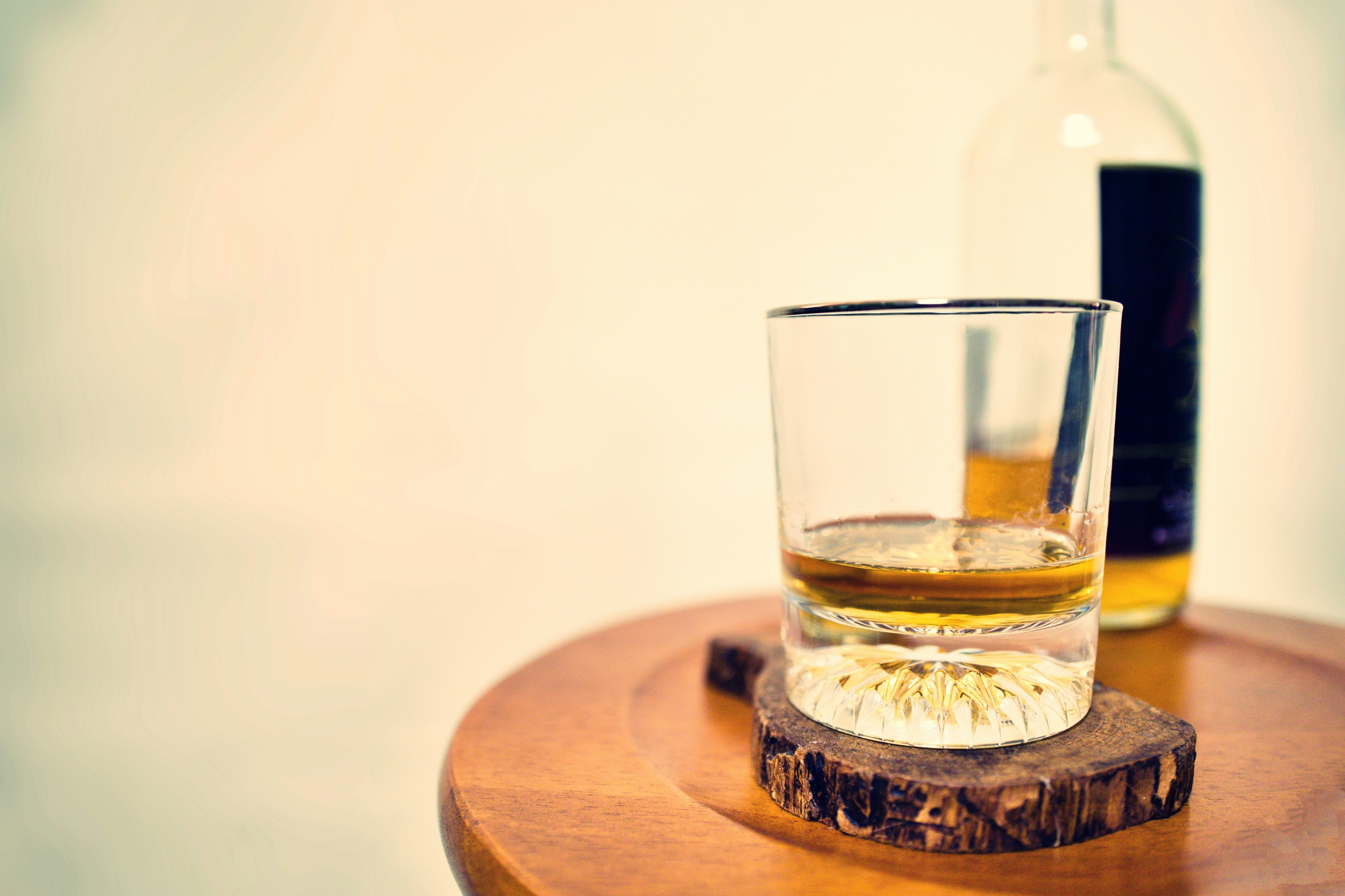 Một ly whisky và một chai trên bàn gỗ