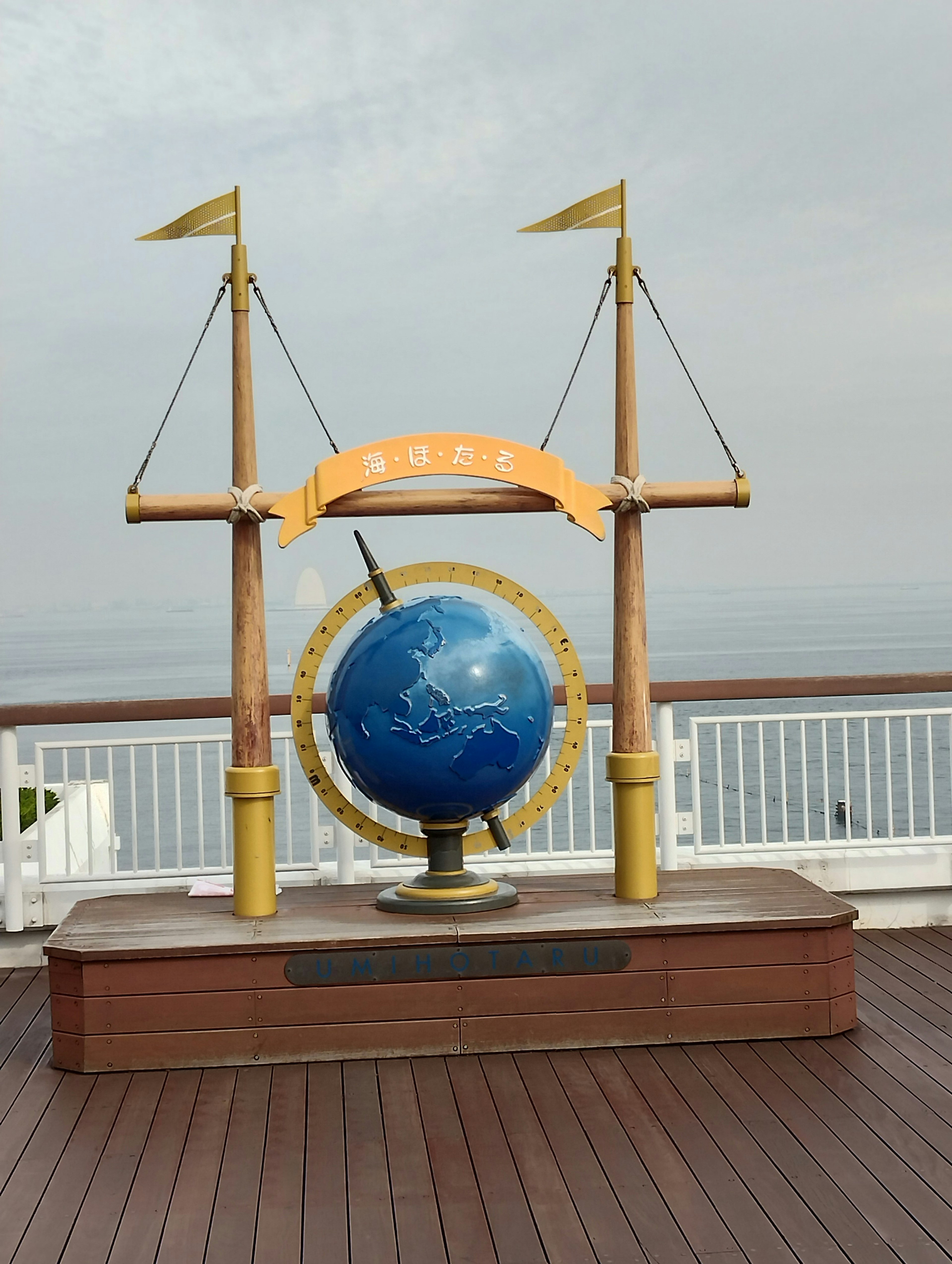 Decorative stand with a large blue globe against a sea backdrop