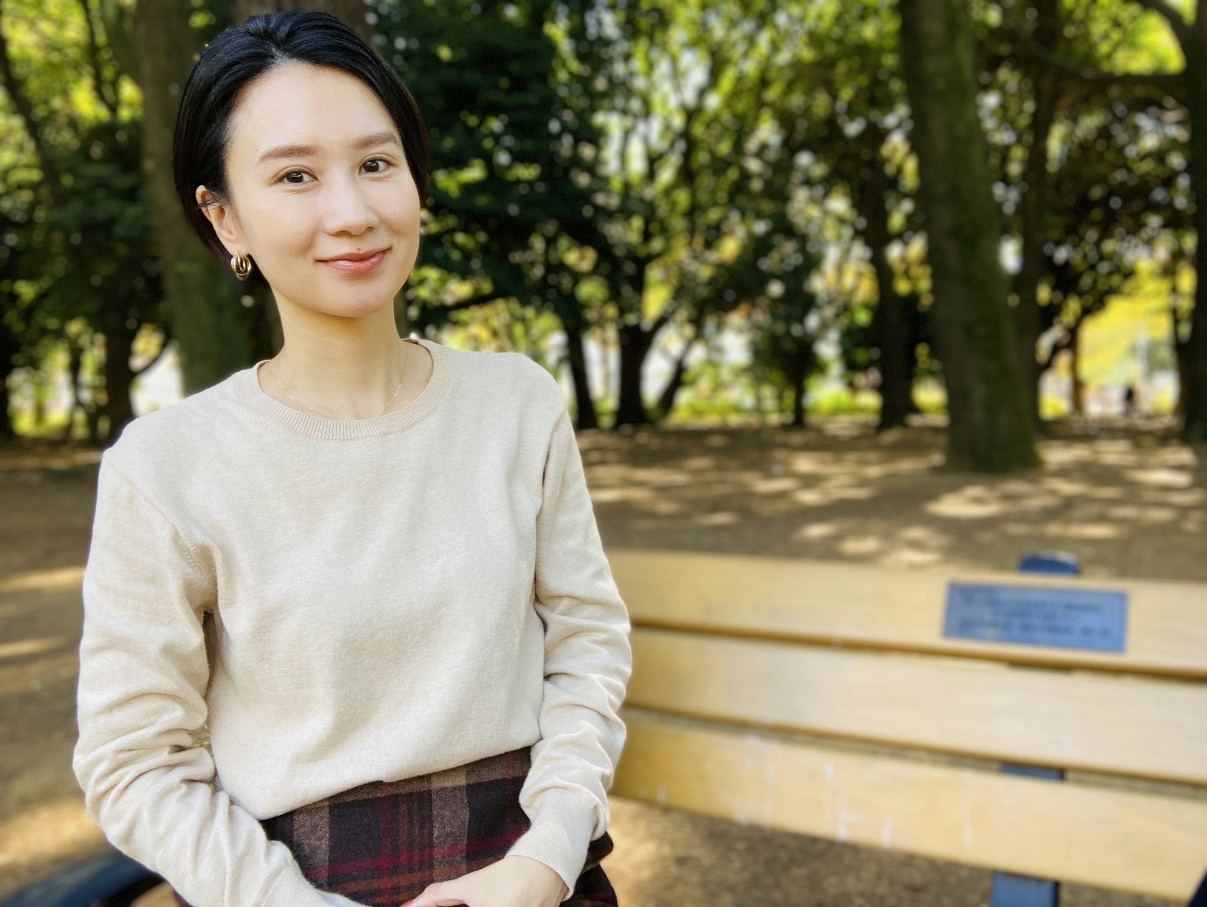 Portrait of a woman sitting on a park bench smiling in natural light