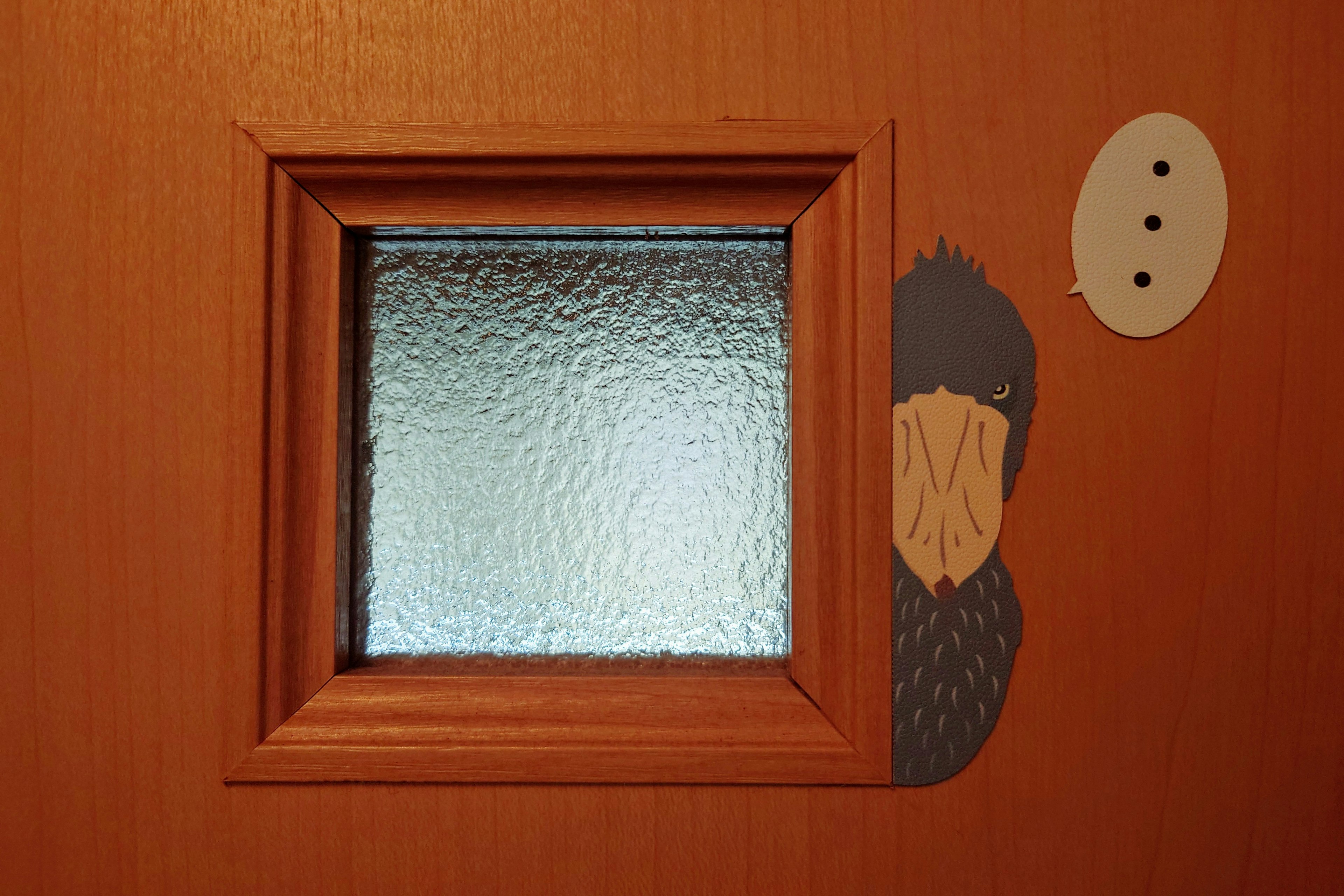 Puerta de madera con ventana de vidrio texturizado y personaje ilustrado