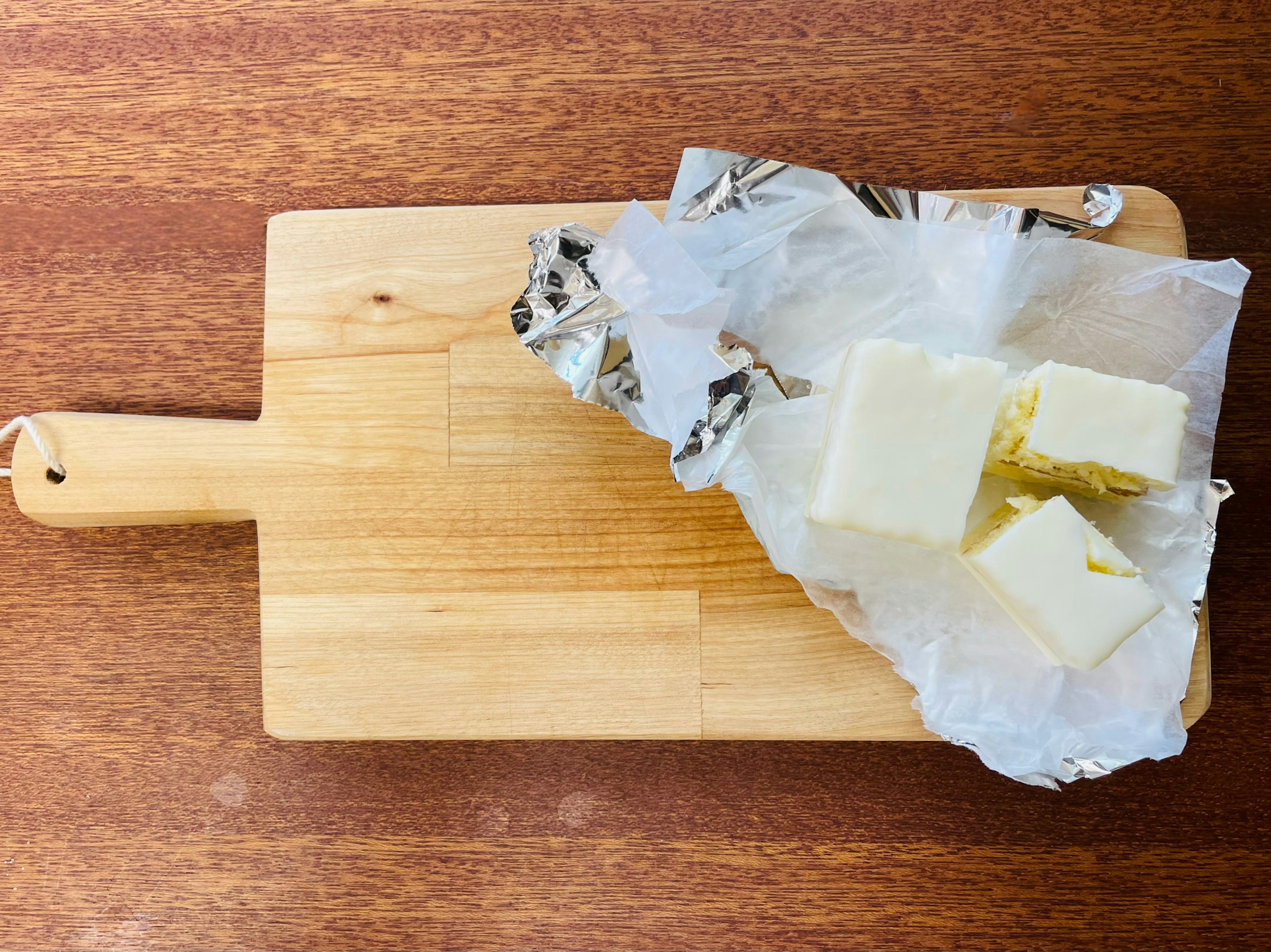 Cubi di burro avvolti in carta su un tagliere di legno