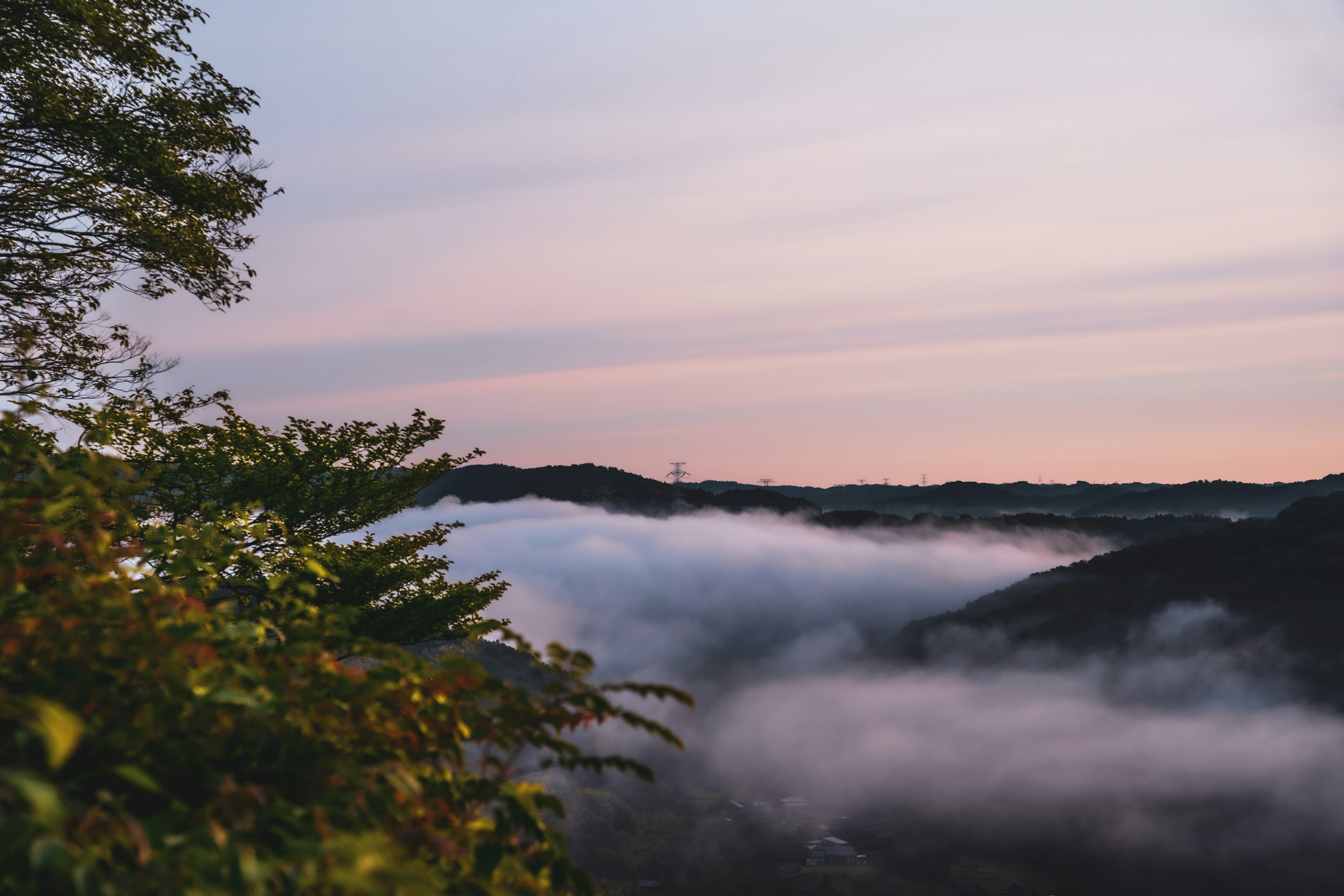 In Nebel gehüllte Berge mit einem sanften Sonnenuntergangshimmel