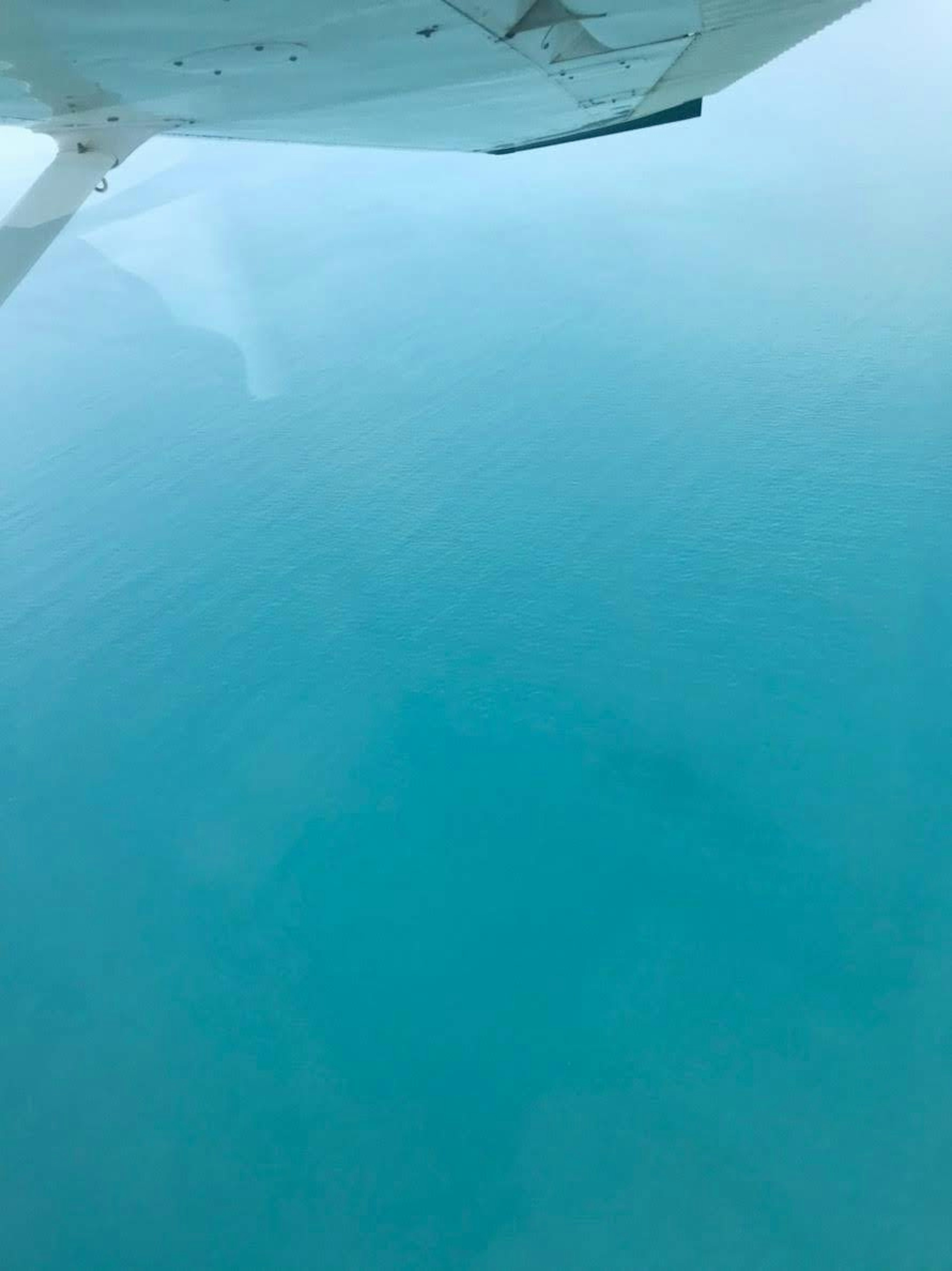 Vue aérienne de la mer turquoise depuis une fenêtre d'avion