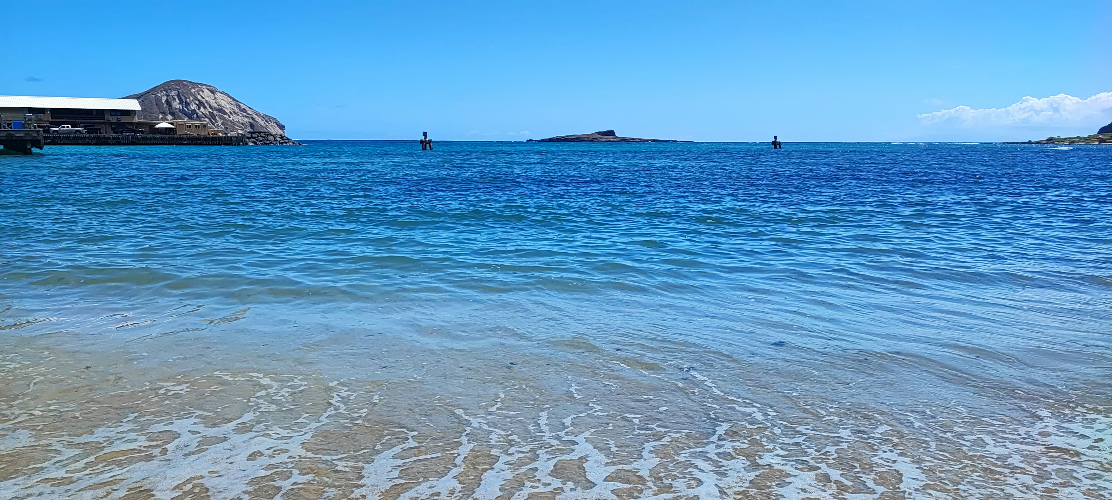 ทิวทัศน์ชายหาดที่มีทะเลสีน้ำเงินและคลื่นเบา