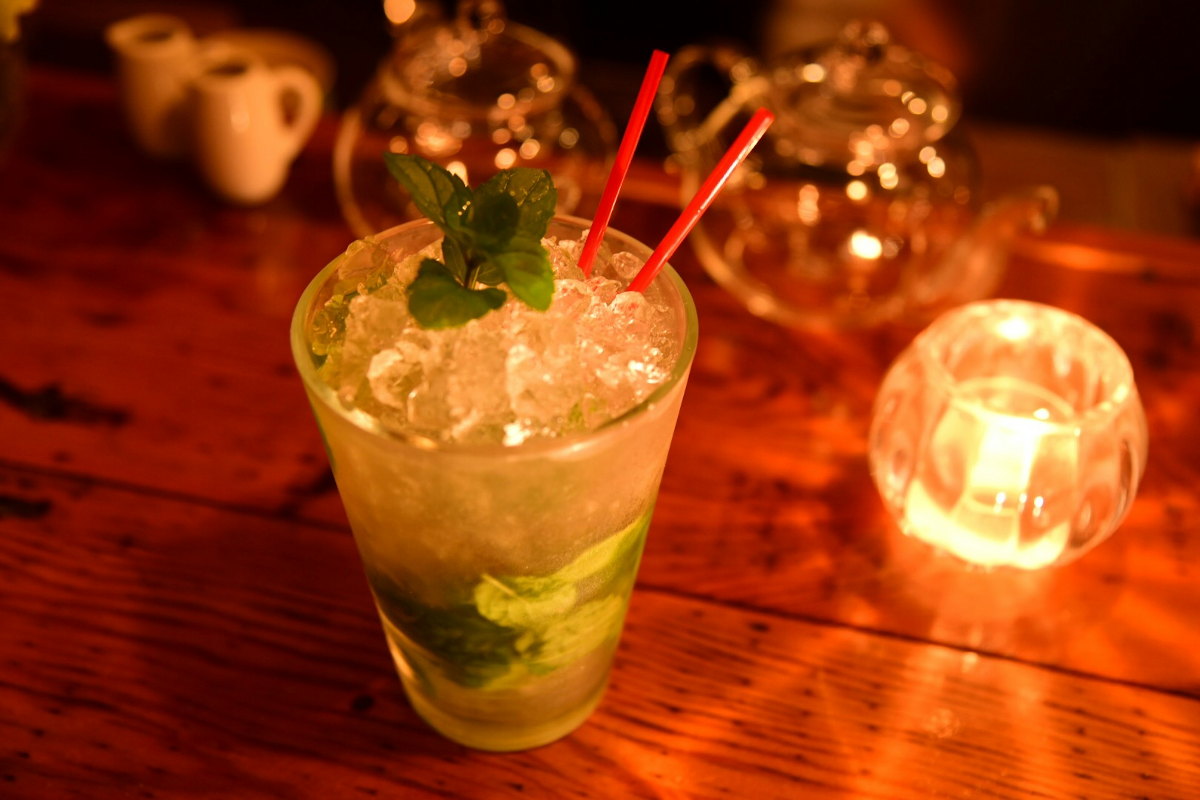 A green mojito cocktail with ice and mint leaves in a glass on a table