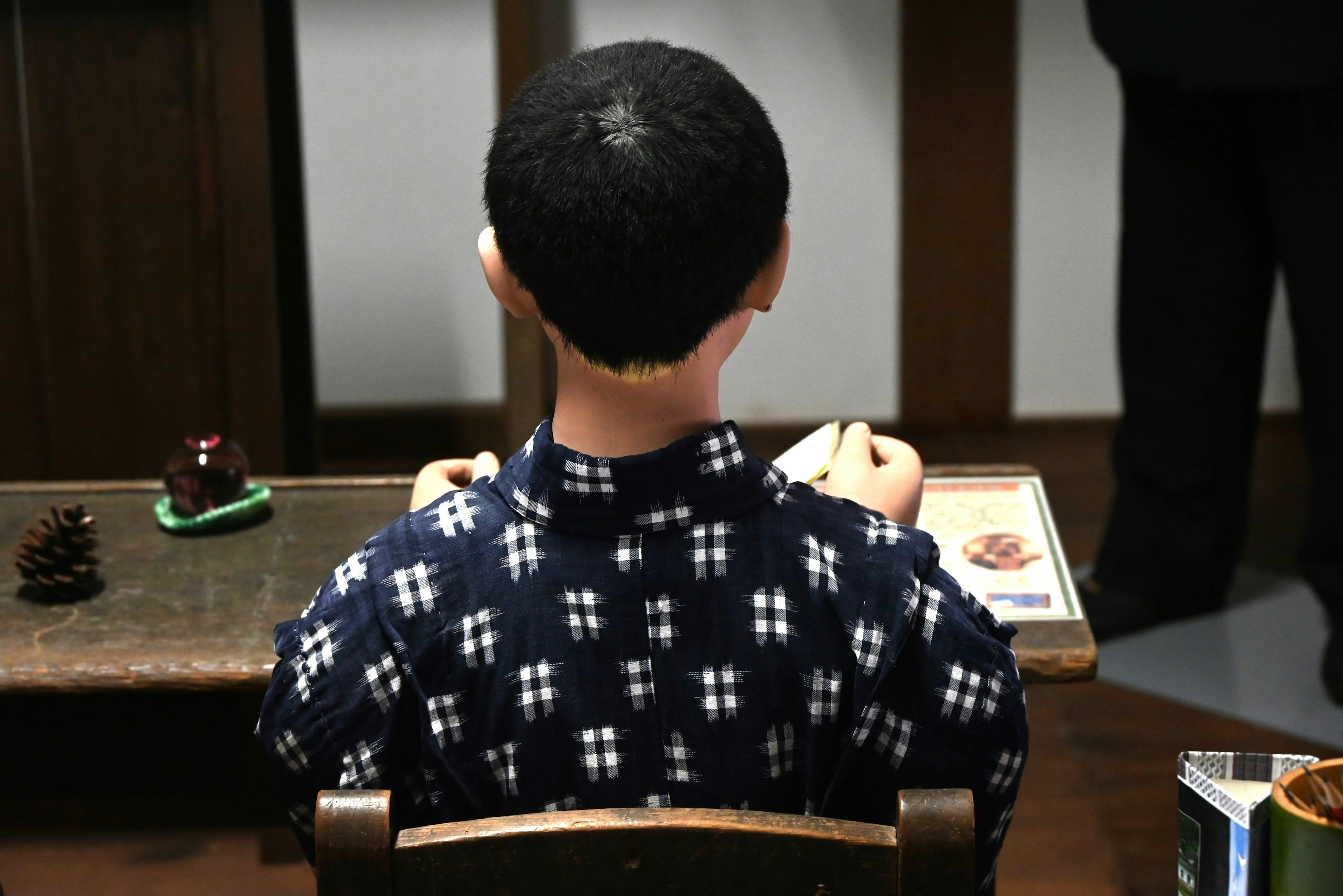 Back view of a boy doll sitting in a traditional Japanese room