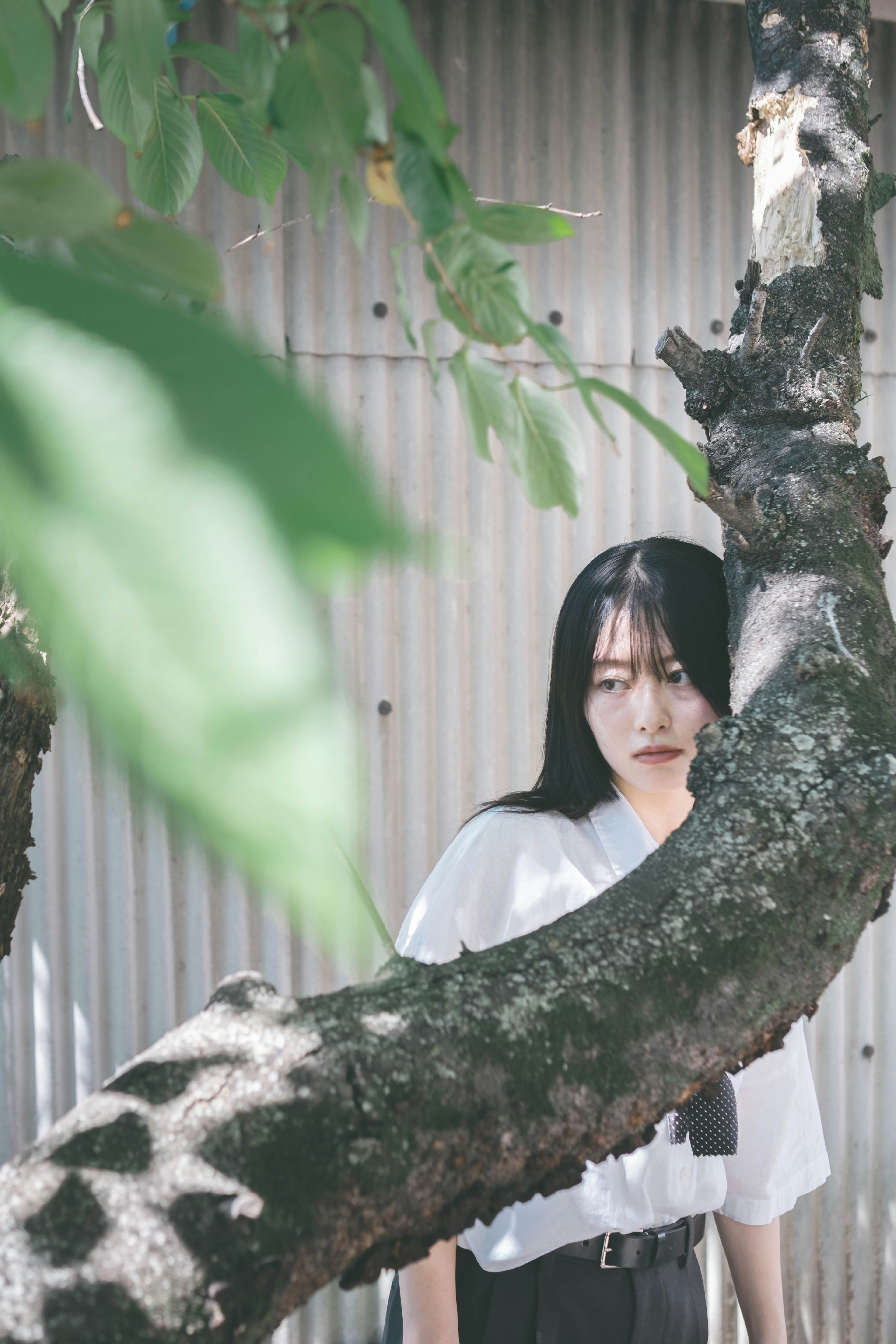 Portrait of a woman standing behind a tree branch