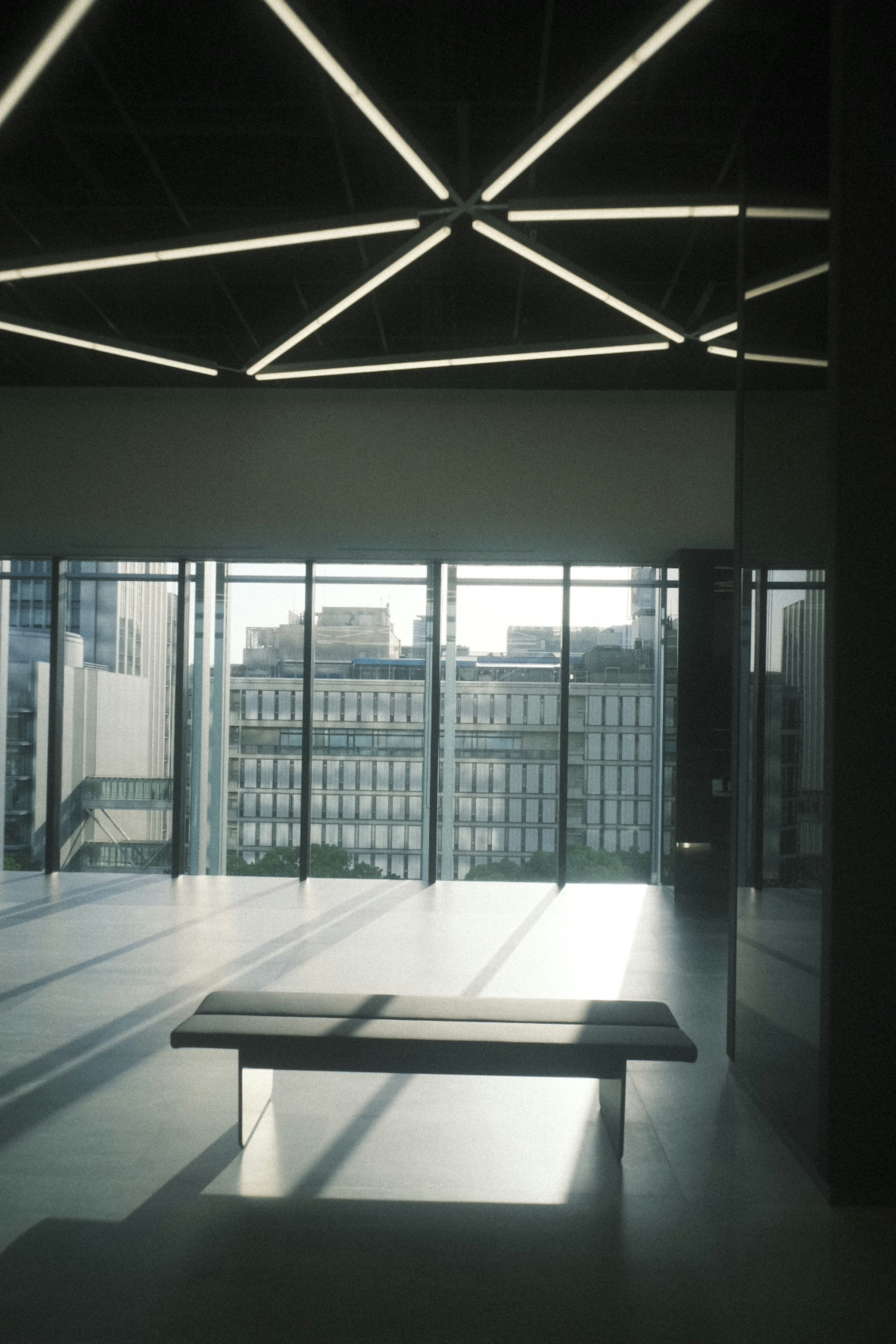 Modern interior space with large windows and a bench illuminated by natural light