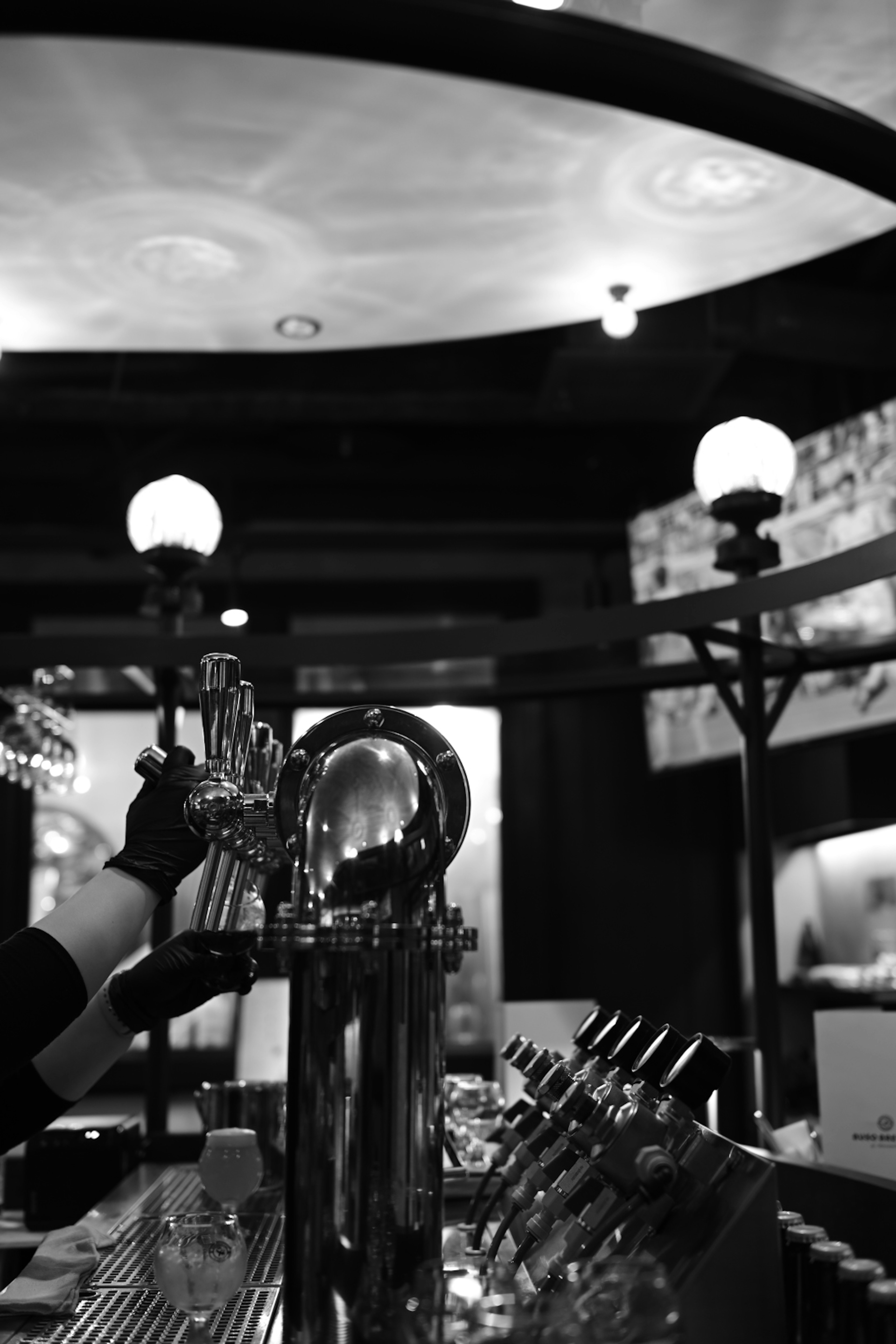 Black and white photo of a hand pouring beer at a bar counter