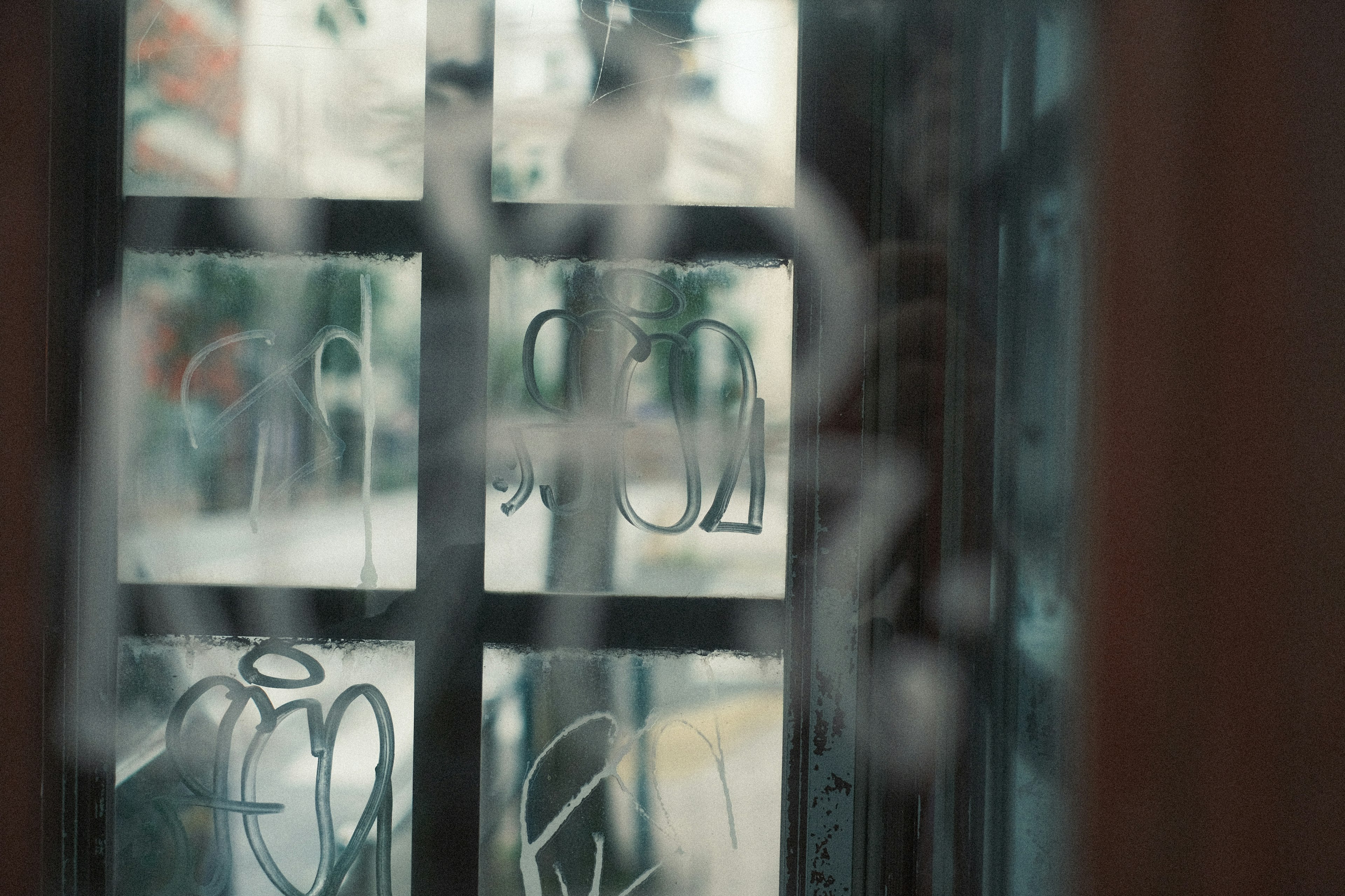 A photo of a foggy glass phone booth interior with blurred external scenery