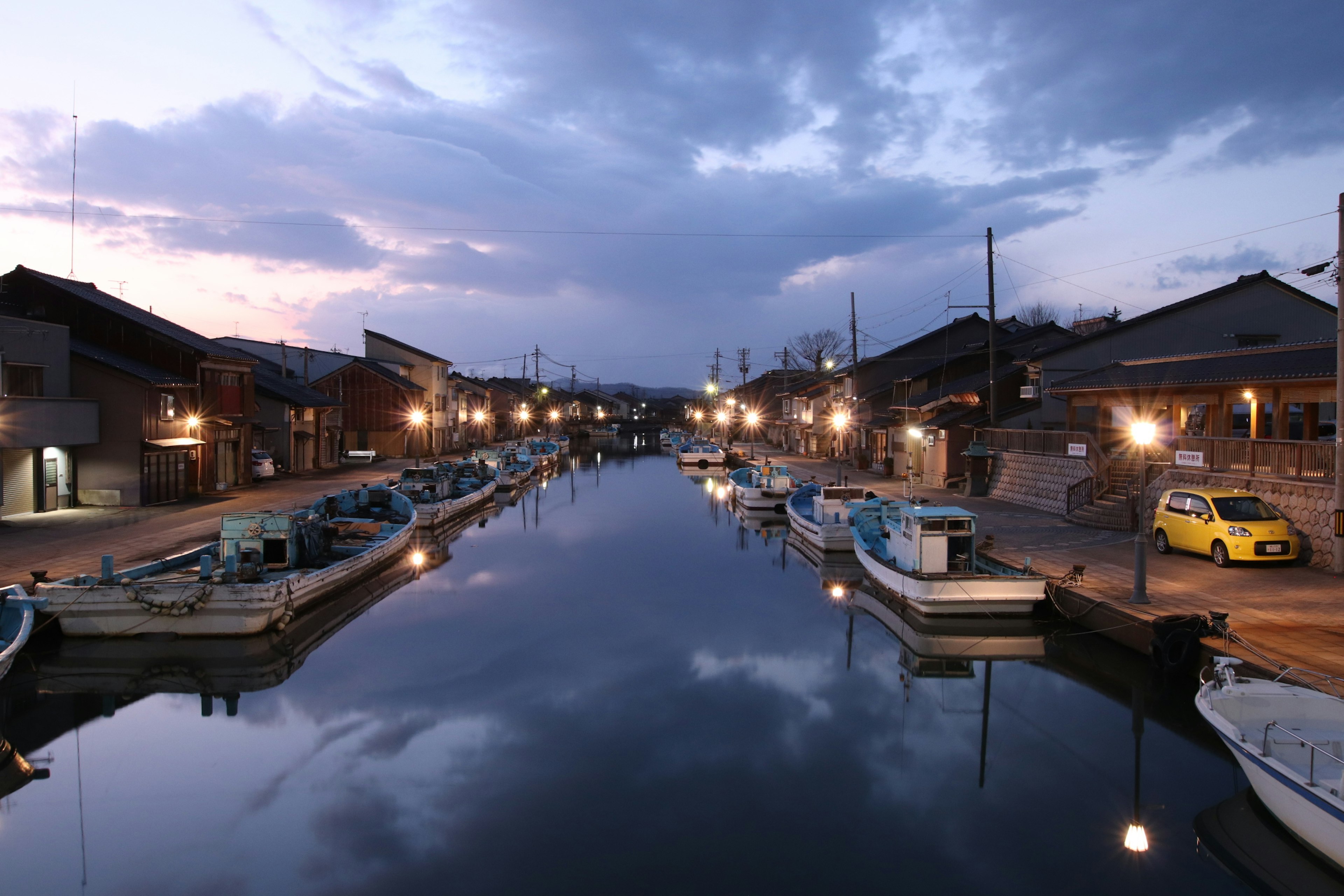 Pemandangan kanal yang tenang saat senja dengan perahu yang berjejer