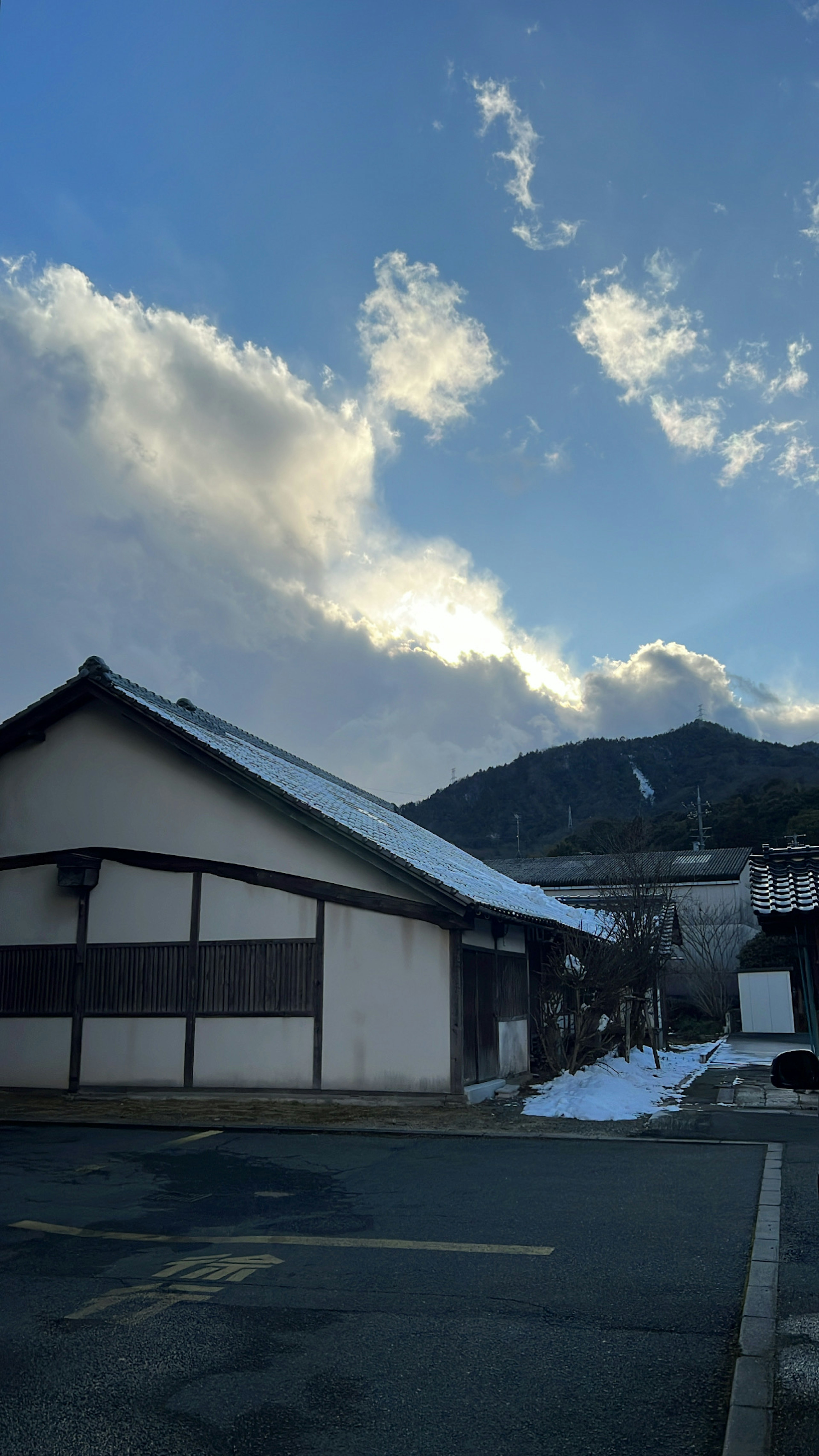 Traditional Japanese building with snow and mountains under a blue sky