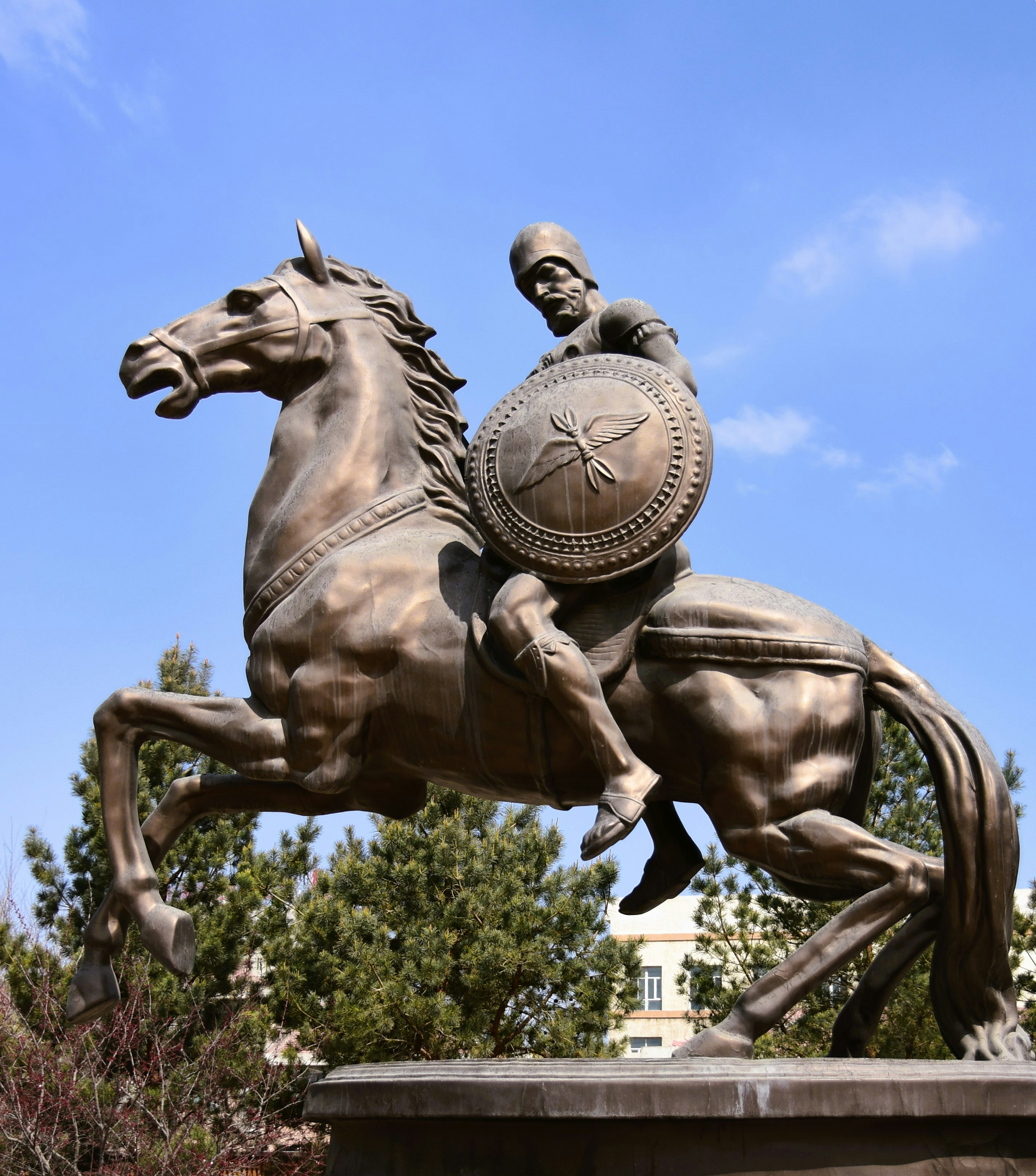 Estatua de bronce de un guerrero montado sosteniendo un escudo sobre un caballo