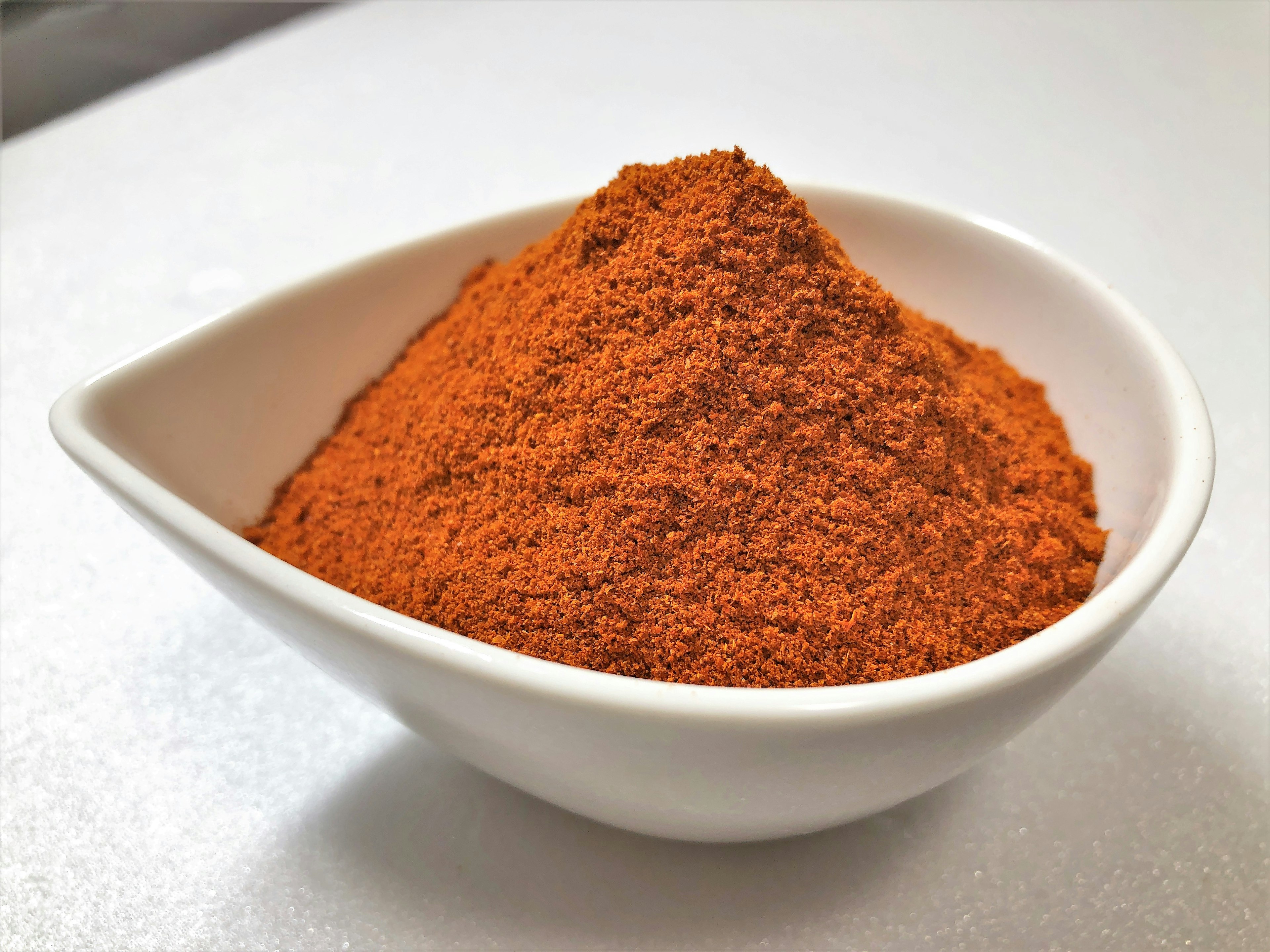 A mound of red spice powder in a white dish