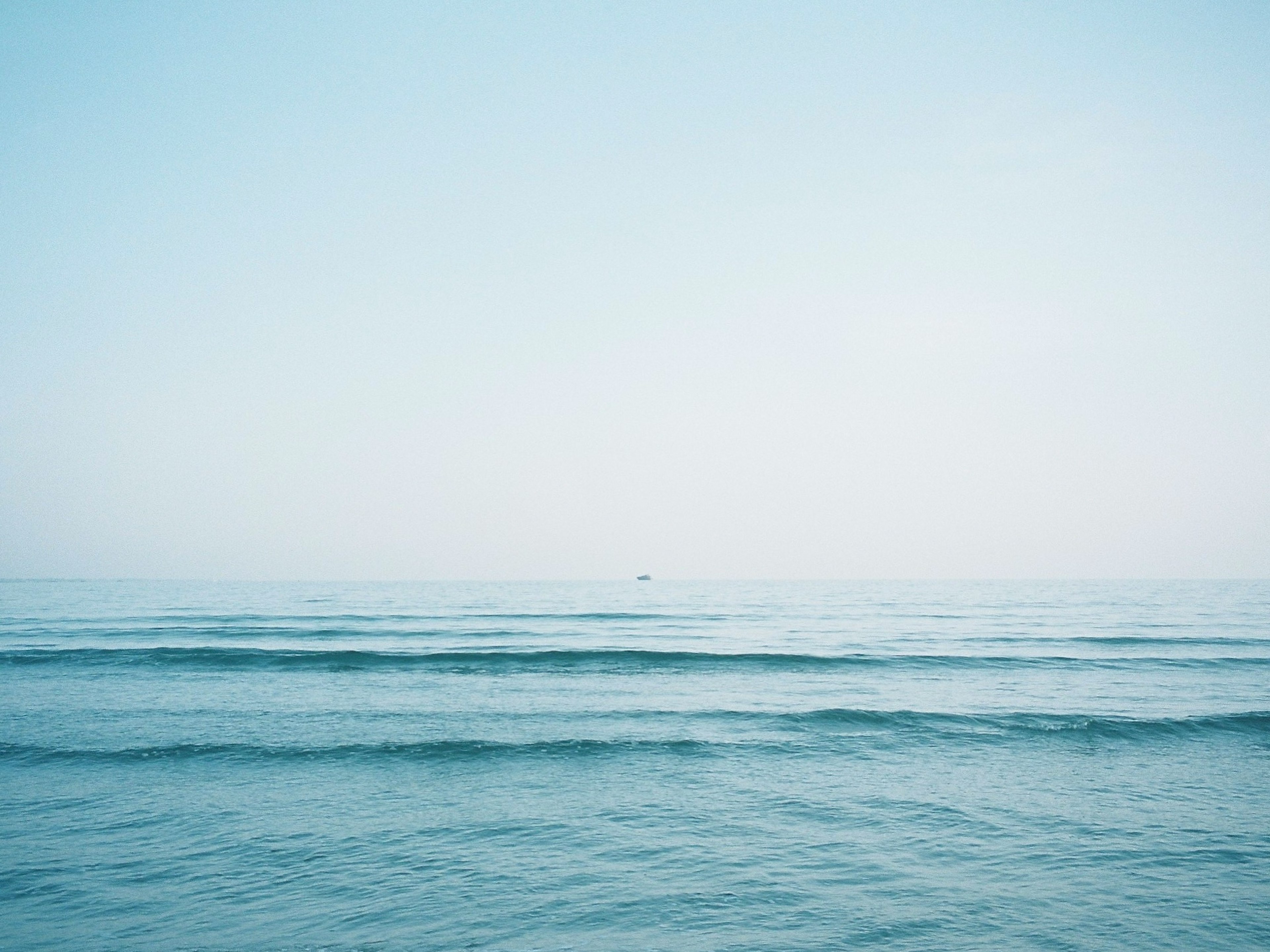 穏やかな青い海と空の風景 遠くに小さな船が見える