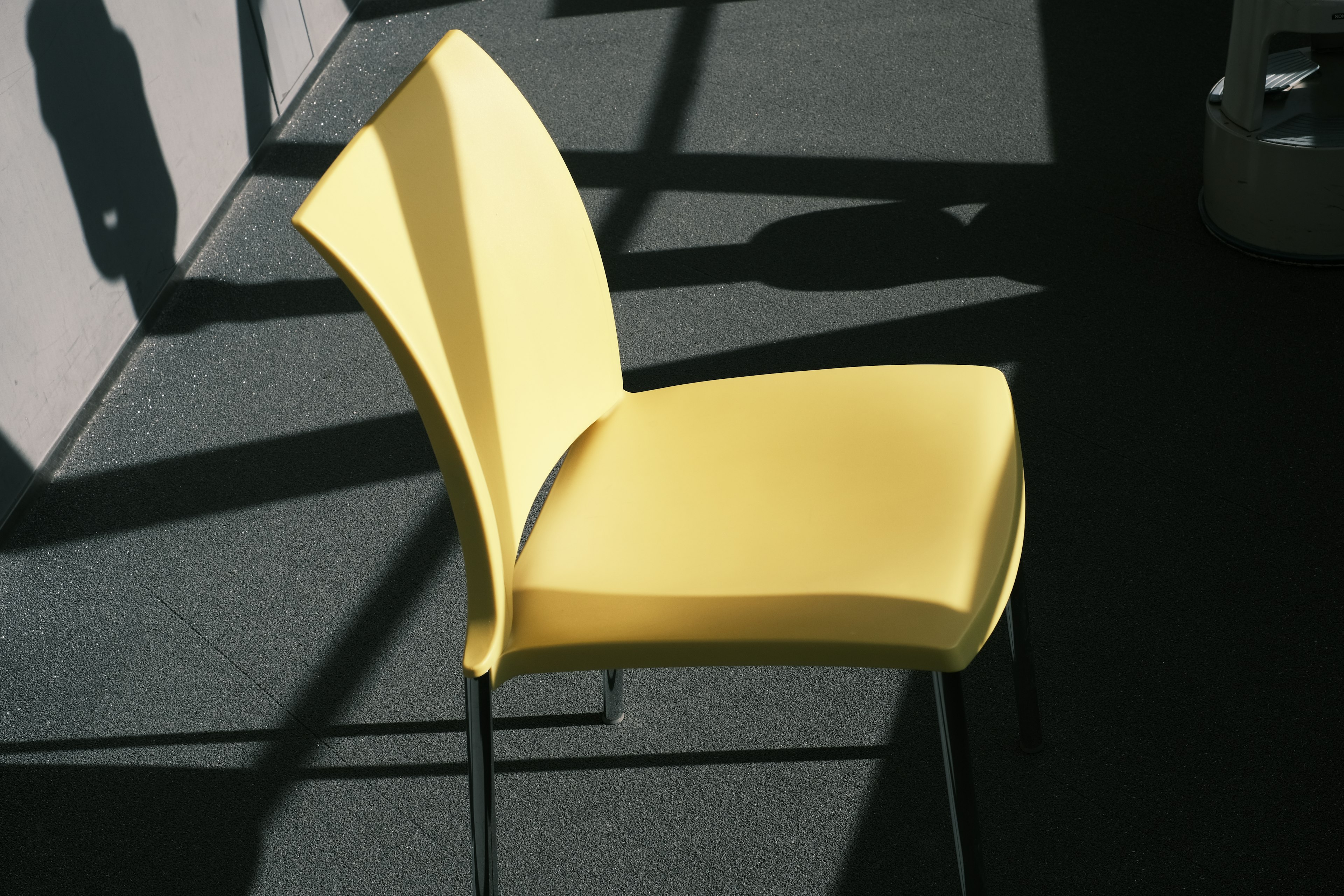 A yellow chair positioned in shadows with geometric patterns