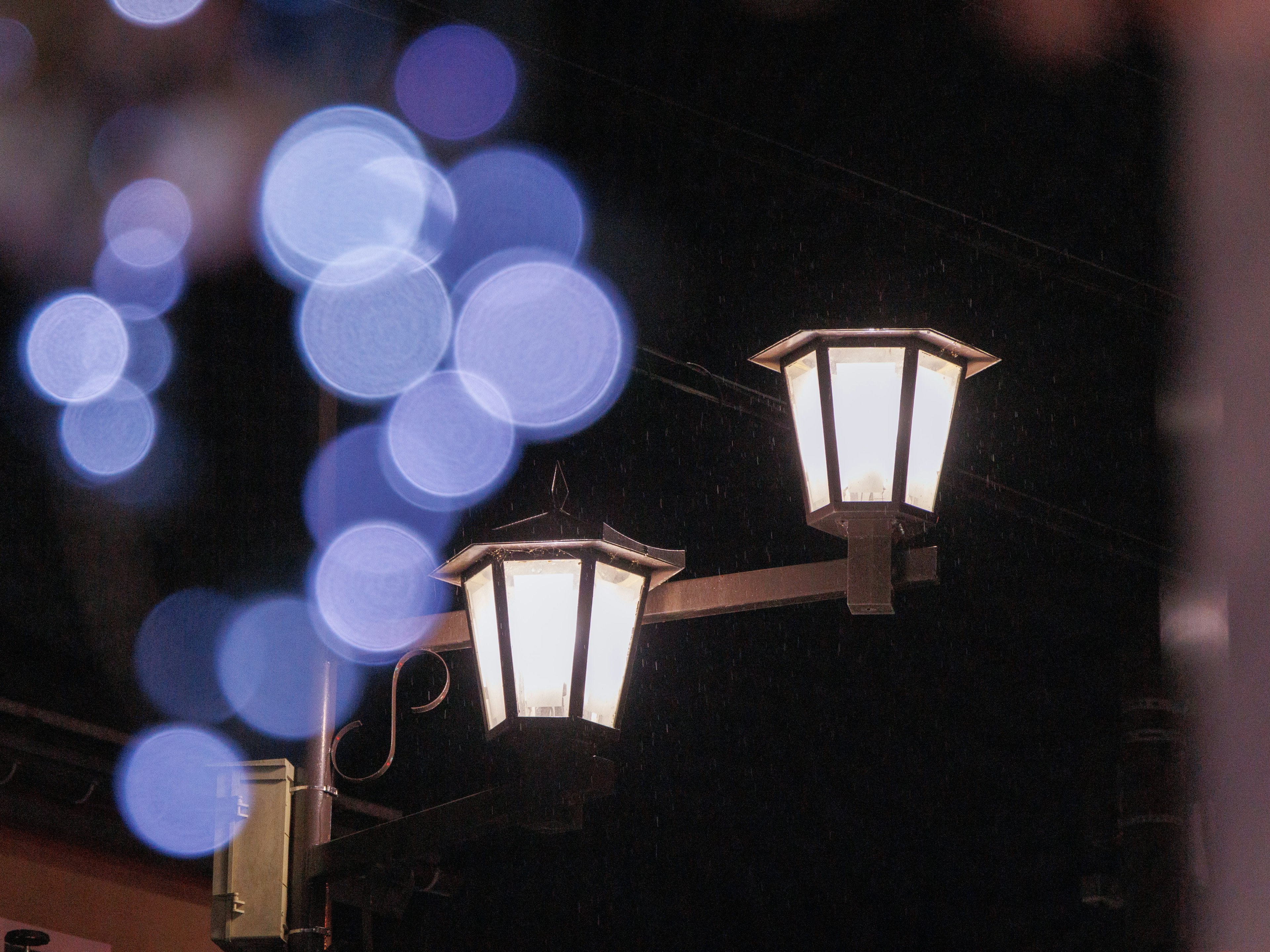 Farolas iluminadas por la noche con luces azules borrosas de fondo