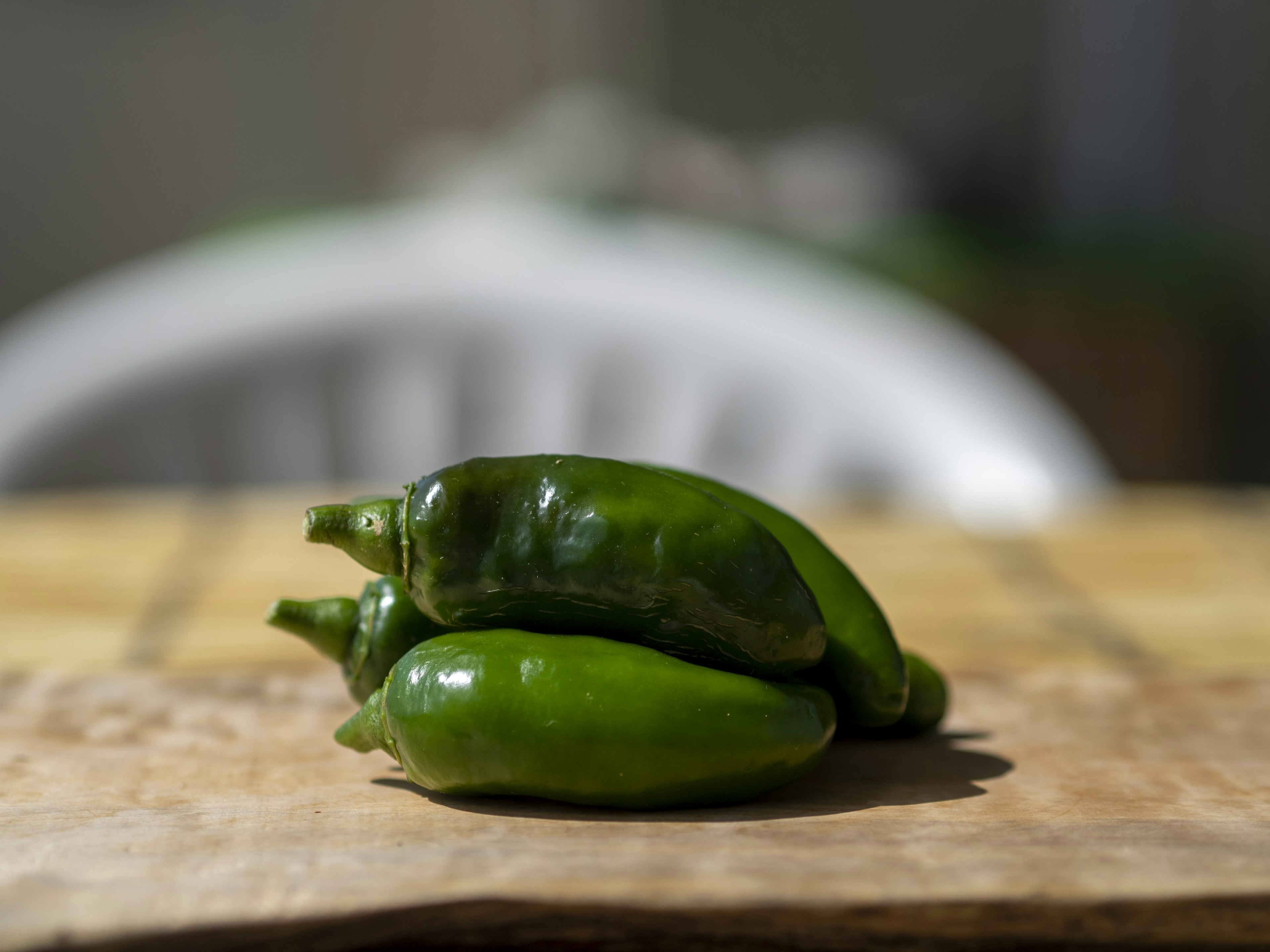 Green chili peppers stacked on a wooden cutting board