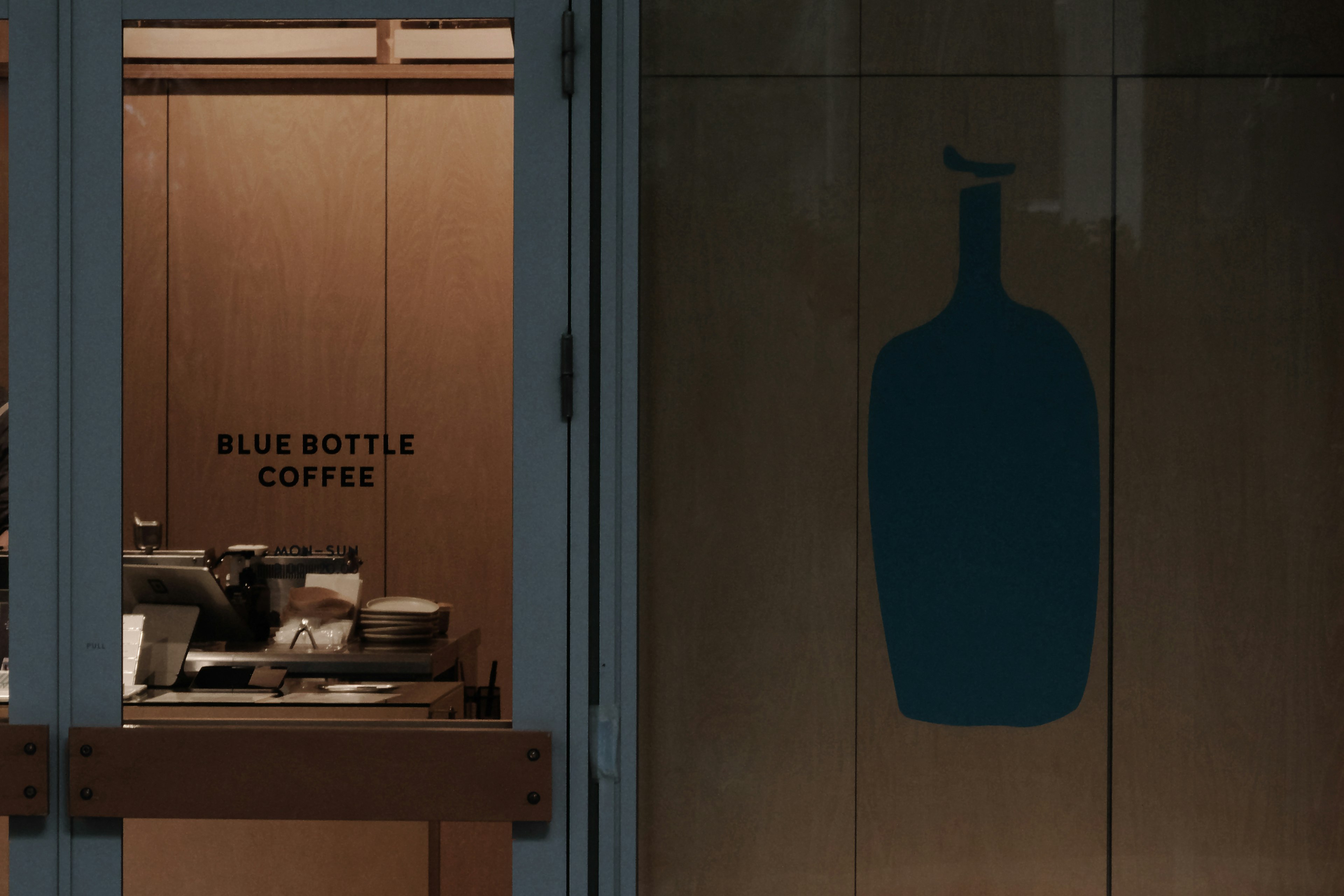 Entrance of Blue Bottle Coffee shop with a glass door design