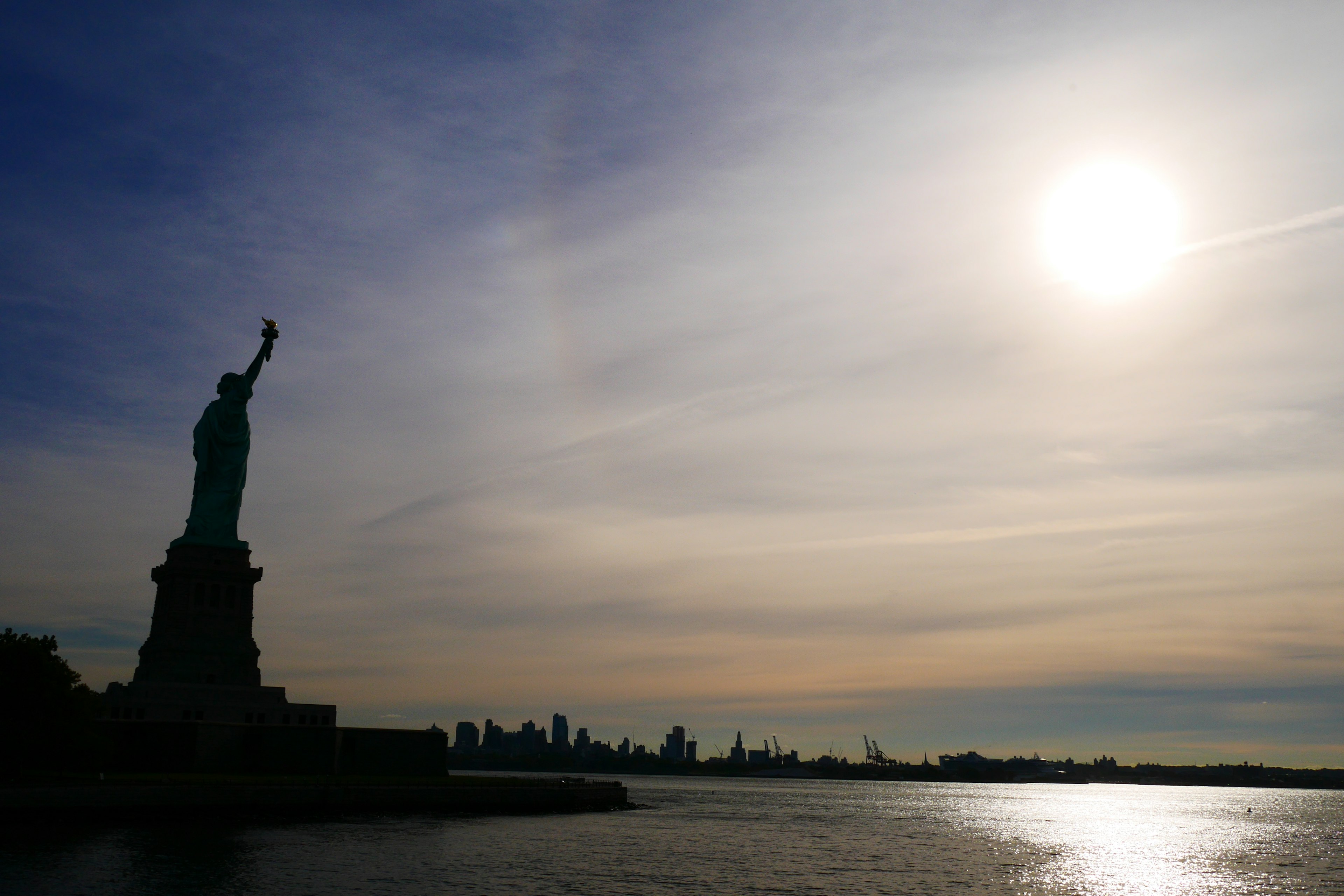 Statue of Liberty silhouette against a sunset sky