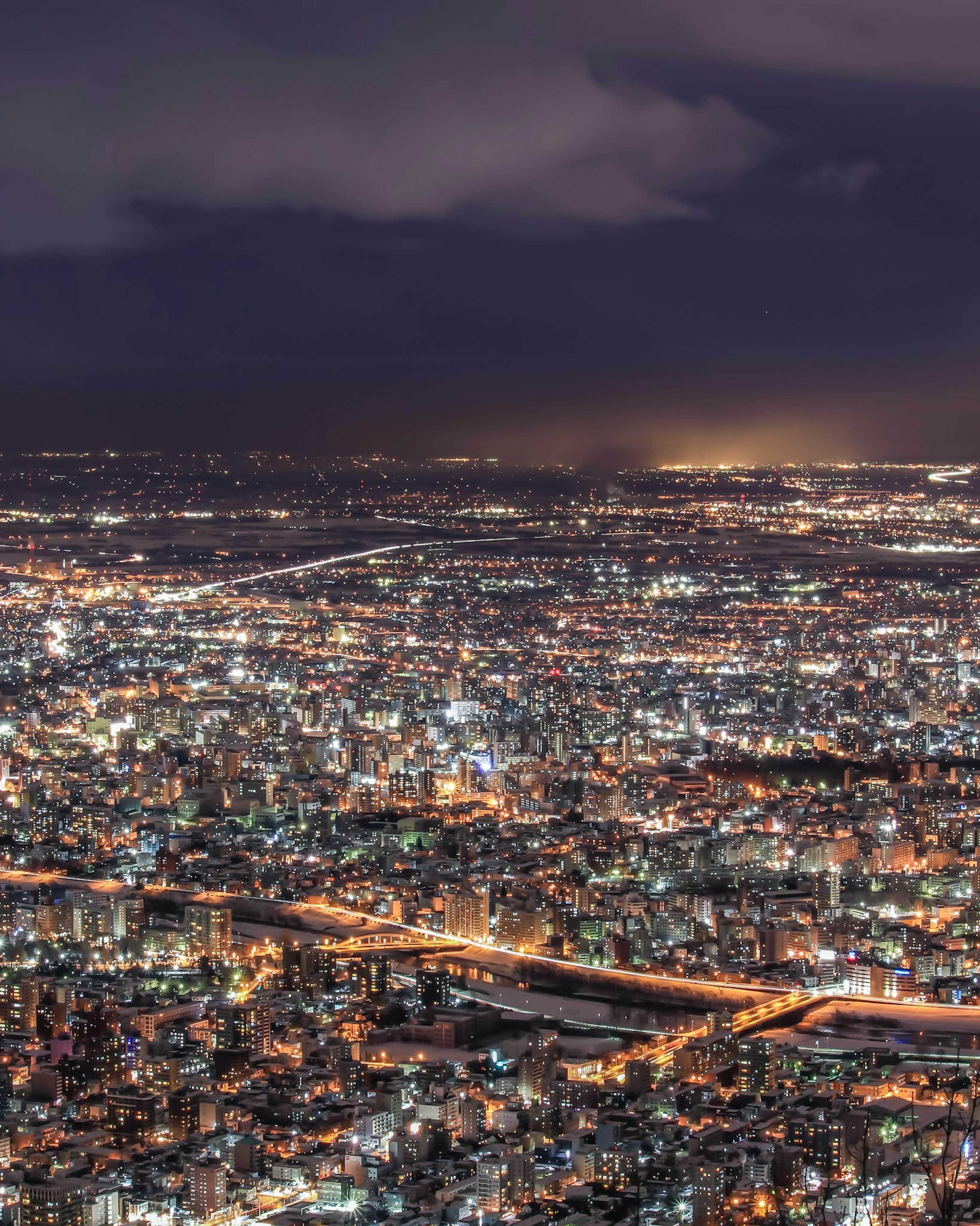 Night view of a cityscape bright lights across the urban landscape visible roads and rivers