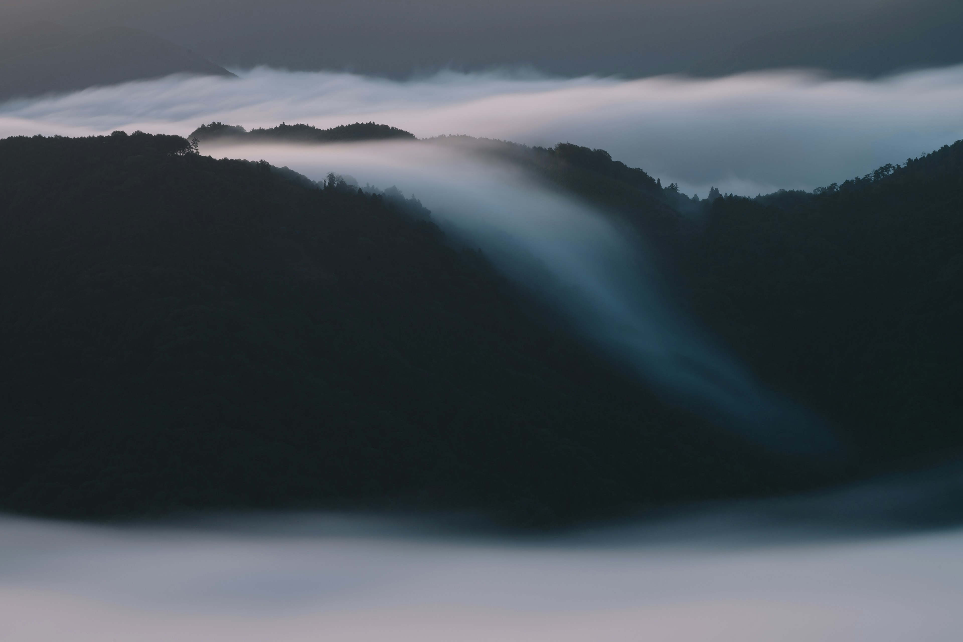 霧に包まれた山々のシルエットが見える風景